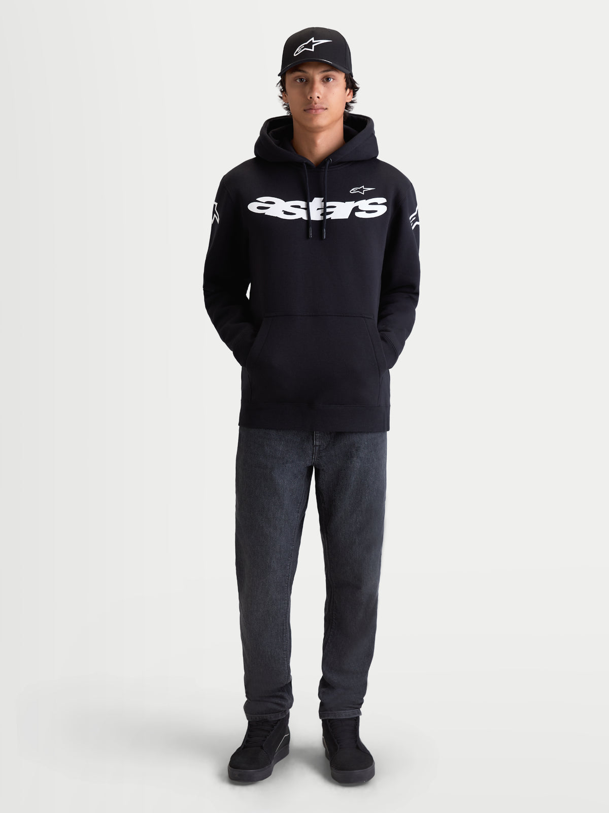 Alpinestars felpa con cappuccio Velocifier, sportswear casual da uomo per uso off-bike, nera e bianca, in misto cotone premium. Caratterizzata dalla scritta Astars curva sul petto e loghi sulle spalle, mostrata su un modello con cappellino coordinato.