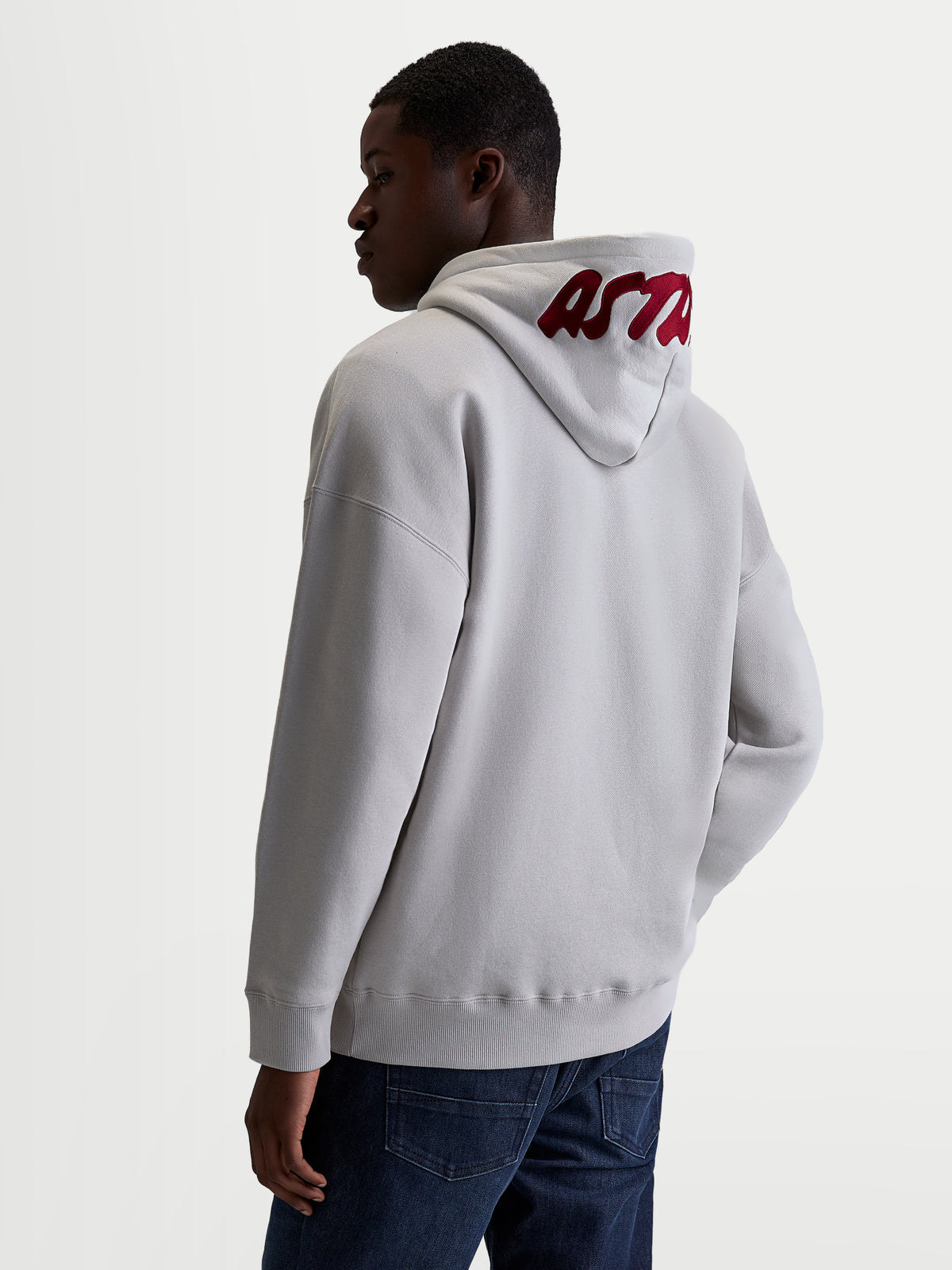 Alpinestars felpa con cappuccio Pioneer Oversize, felpa sportswear casual unisex, grigio cemento con logo rosso ricamato sul cappuccio, vestibilità oversize rilassata, vista posteriore su modello.