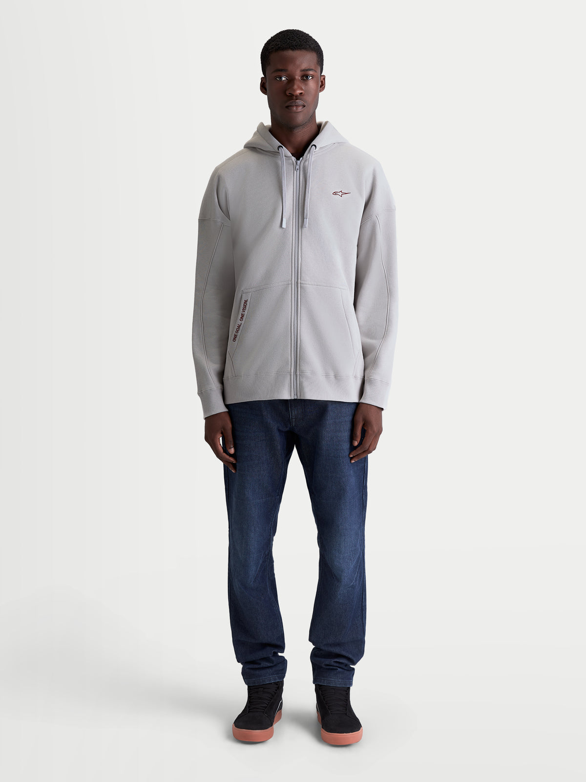 Alpinestars Felpa Con Cappuccio Pioneer Oversize, felpa sportswear lifestyle con zip, grigia, vestibilità oversize rilassata, cerniera Vislon e tasca a marsupio, loghi ricamati, vista frontale a figura intera su modello