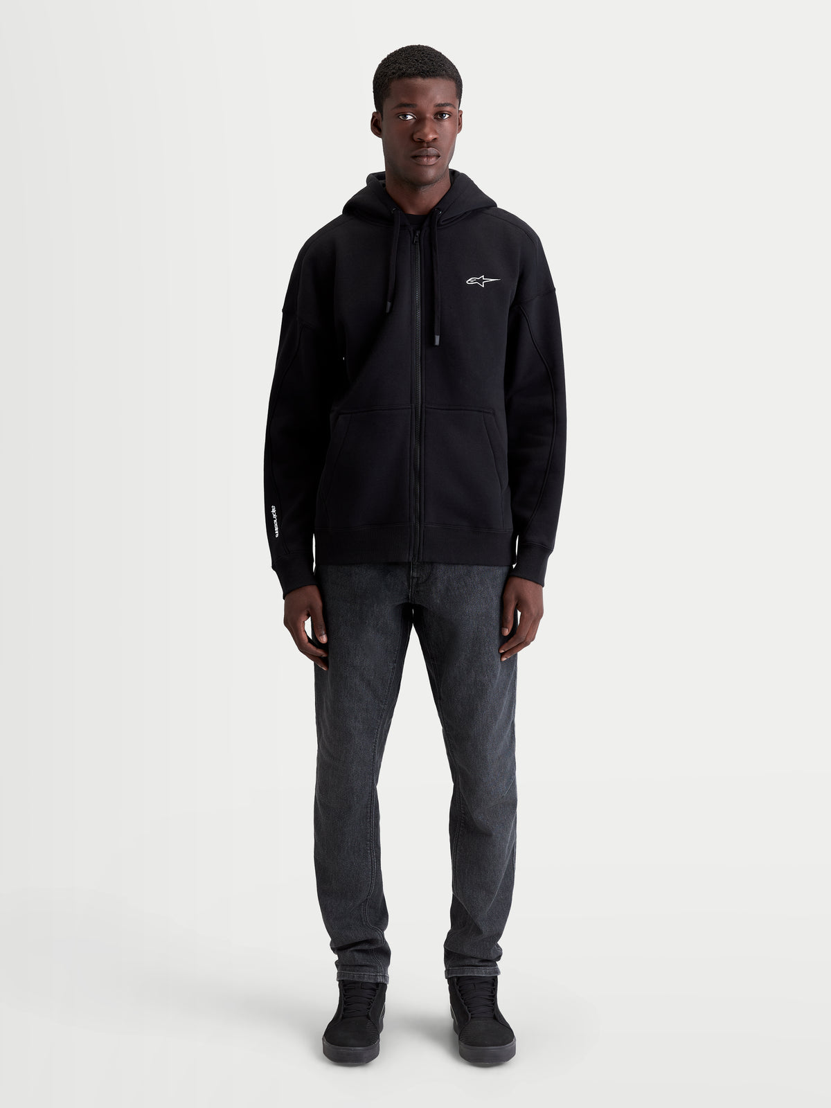 Alpinestars felpa con cappuccio Entity Oversized, felpa con zip in pile, unisex, nera, vestibilità rilassata, logo Astars bianco ricamato sul petto e sulla manica, tasca a marsupio, vista frontale su modello.