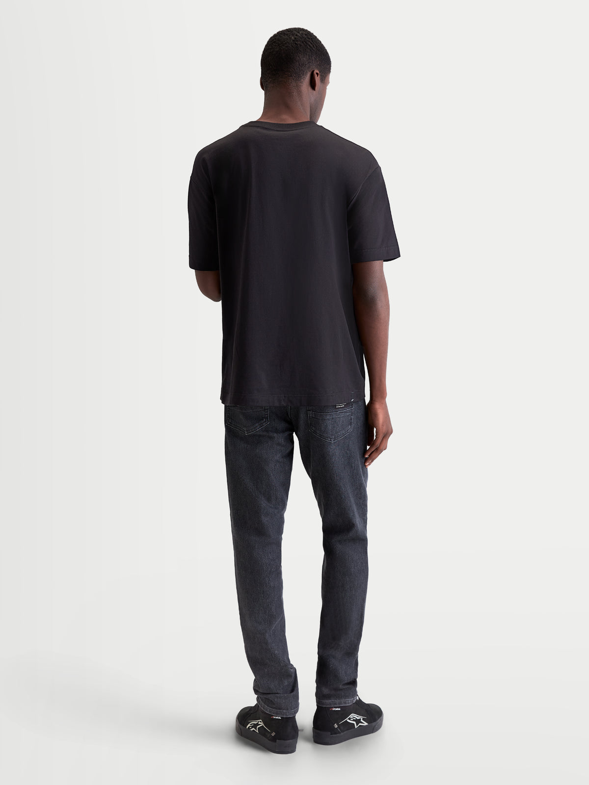 Alpinestars Maglietta Infinity Oversized CSF, maglietta a maniche corte da uomo, vista posteriore su modello, nera, in misto cotone, vestibilità rilassata per comfort quotidiano e stile off-bike