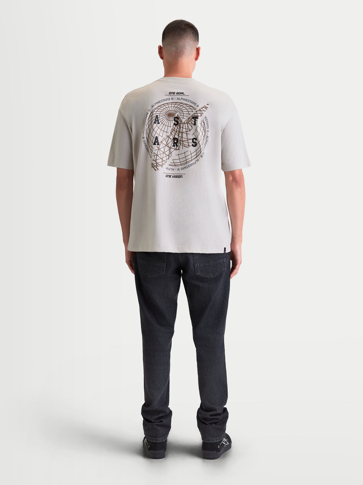 Alpinestars Maglietta Latitude Oversized CSF, maglietta a maniche corte da uomo, grigio cemento, vista posteriore su modello con grande grafica con globo e wordmark Astars sulla schiena, vestibilità oversize rilassata, sportswear.