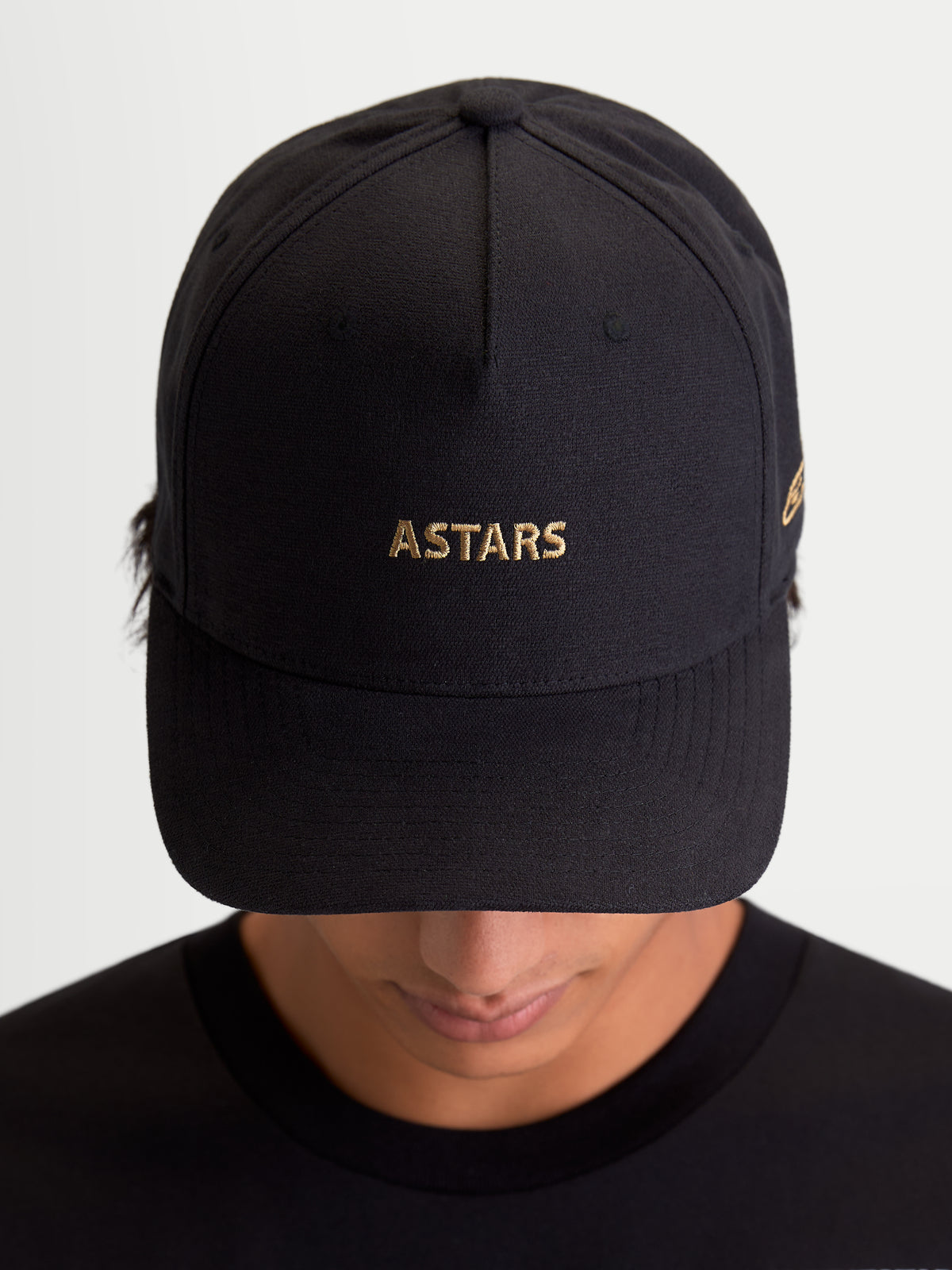 Alpinestars Cappello County Canvas, cappello sportswear nero con ricamo del logo ASTARS dorato sulla parte frontale, visiera curva e corona strutturata, tessuto oxford peached, vista frontale su modello