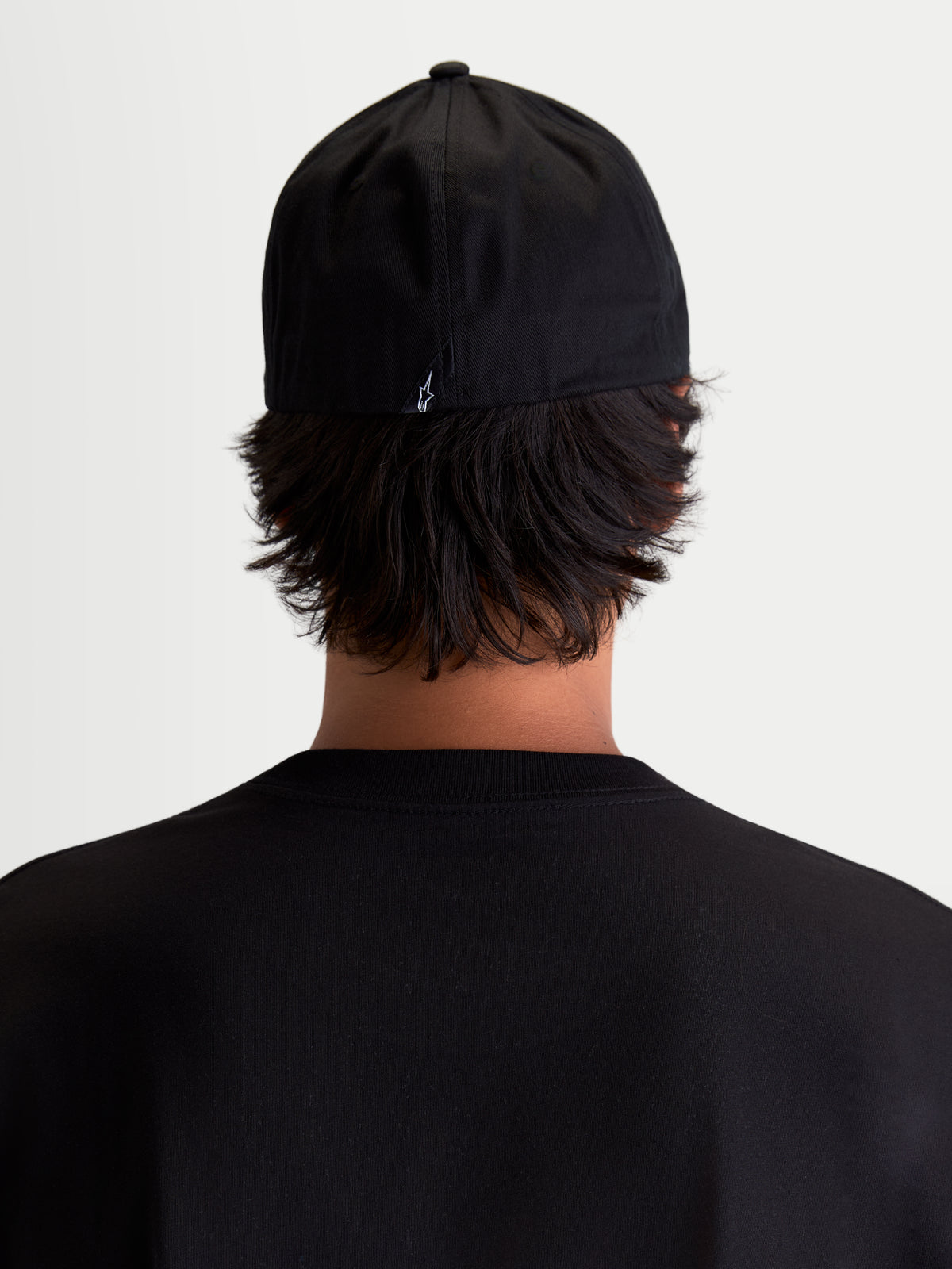 Alpinestars Cappello Arclight, cappello sportswear da baseball, vista posteriore su modello, nero con piccolo logo Astars bianco ricamato sul retro, corona strutturata e retro flessibile in twill di cotone