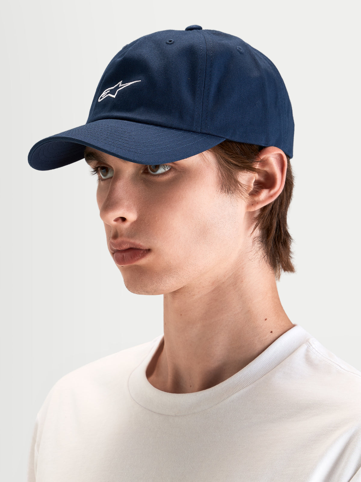 Alpinestars Cappello Dylan Dad, cappello sportswear casual in blu scuro, indossato da un modello, con visiera curva, corona bassa non strutturata e ricamo del logo Astars bianco sul davanti