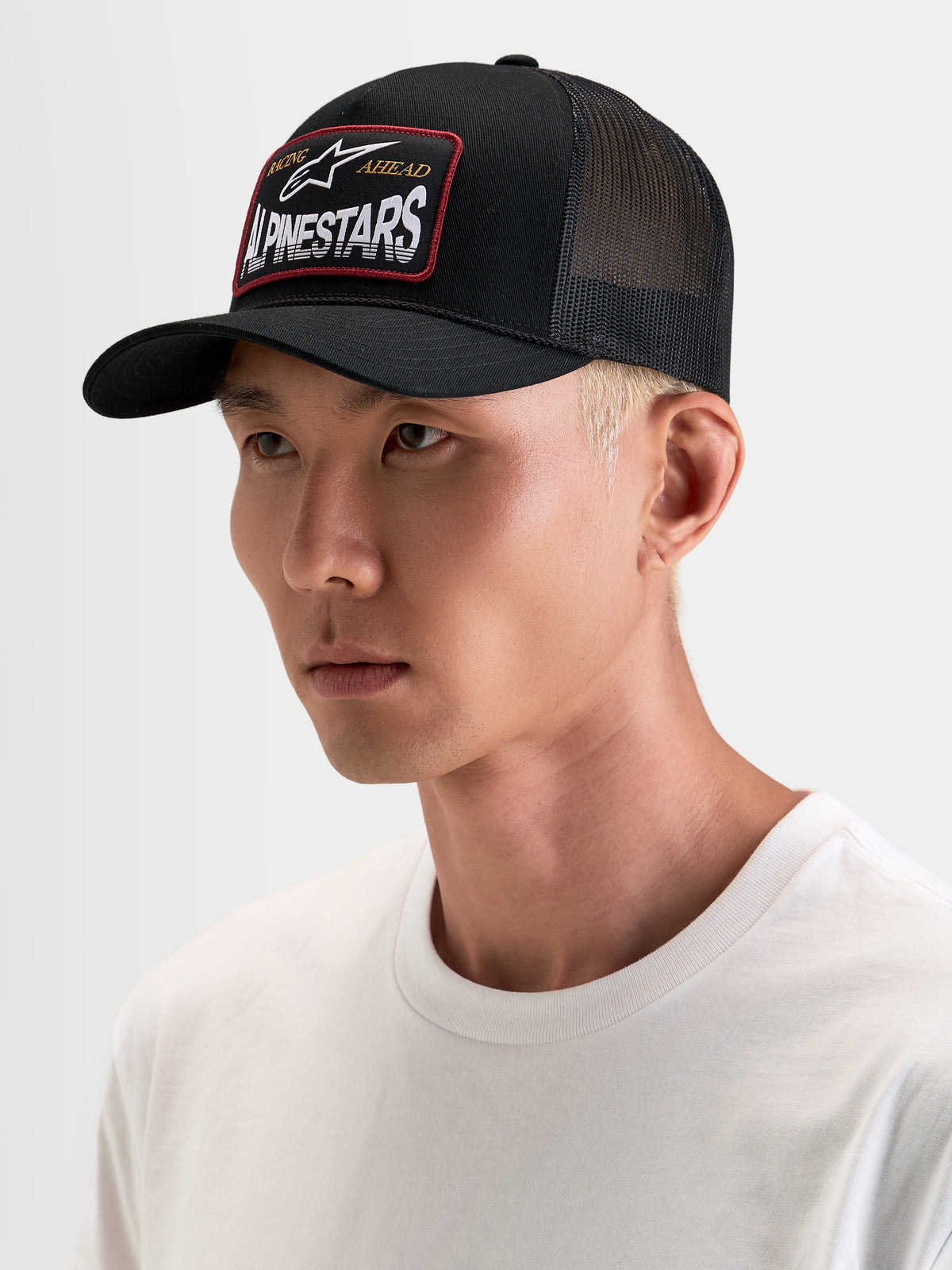 Alpinestars Cappello Hemmings, cappello trucker da sportswear, nero, con pannelli posteriori in rete di poliestere traspirante e patch frontale con logo Alpinestars, indossato da un modello