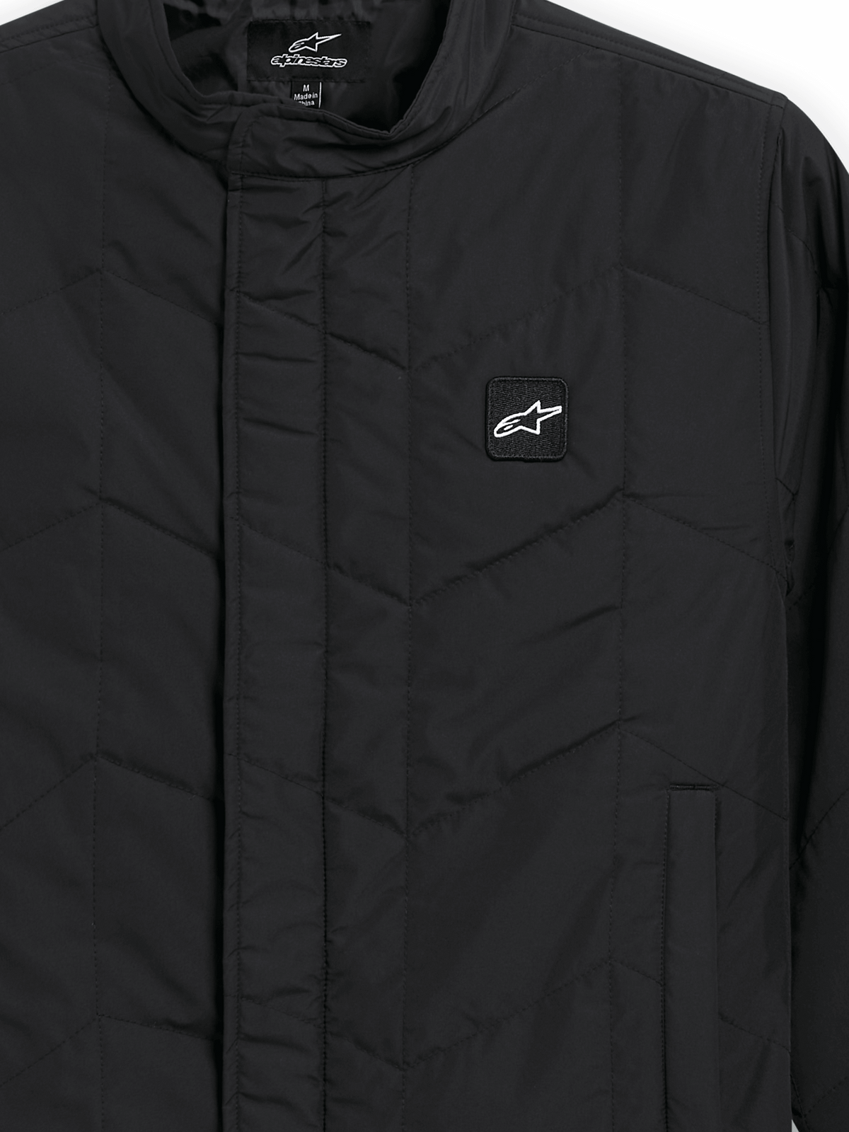 Alpinestars Precedent Jacket, giacca sportswear trapuntata, nero, vista ravvicinata con iconico motivo trapuntato angolato, colletto basso, cerniera frontale coperta e piccola patch con logo sul petto