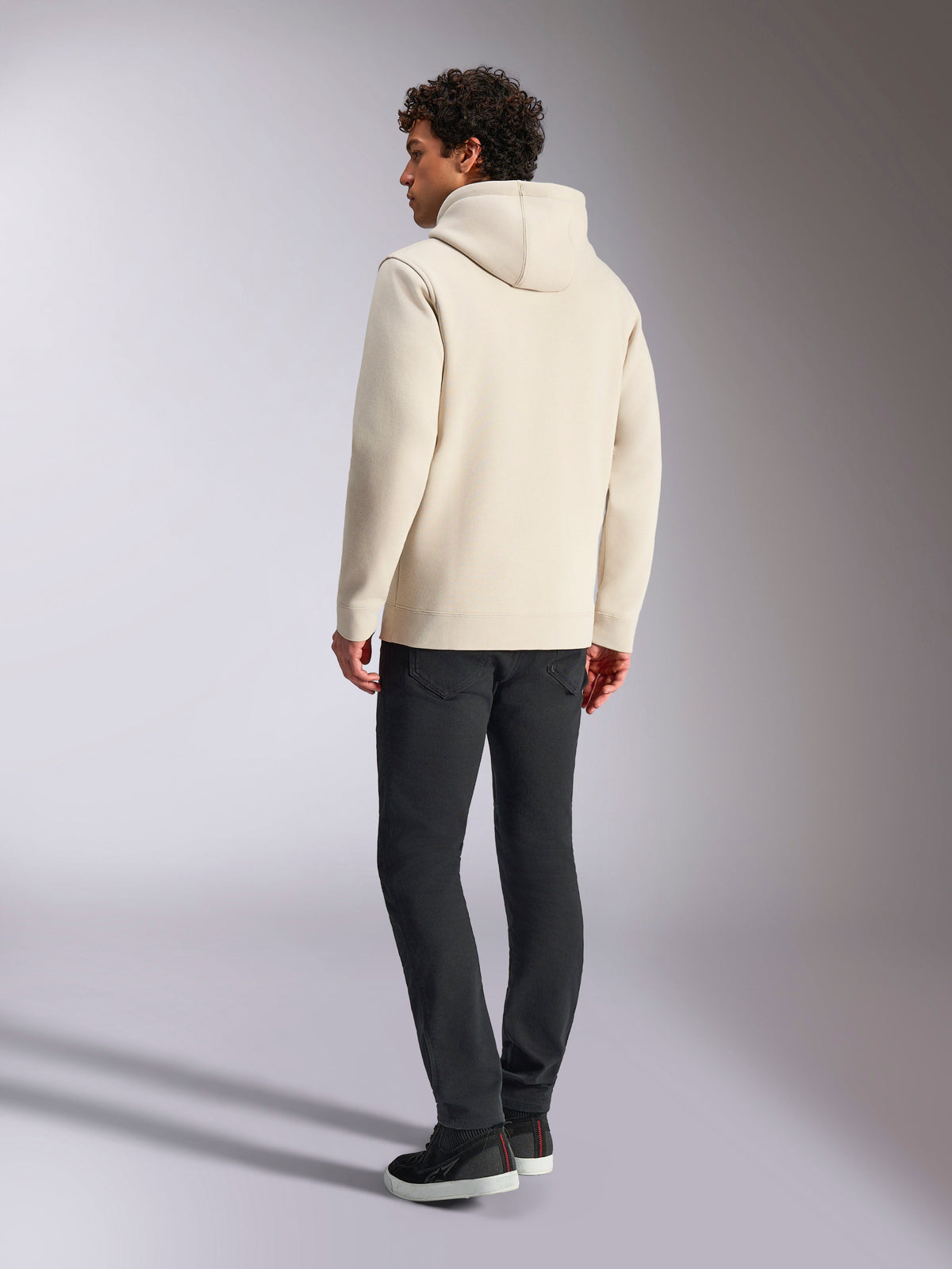 Alpinestars Always V3 Hoodie, bianco sporco, vista posteriore di un modello maschile che indossa la felpa e pantaloni neri, streetwear casual ispirato al motorsport, design minimalista con cappuccio e orlo a costine