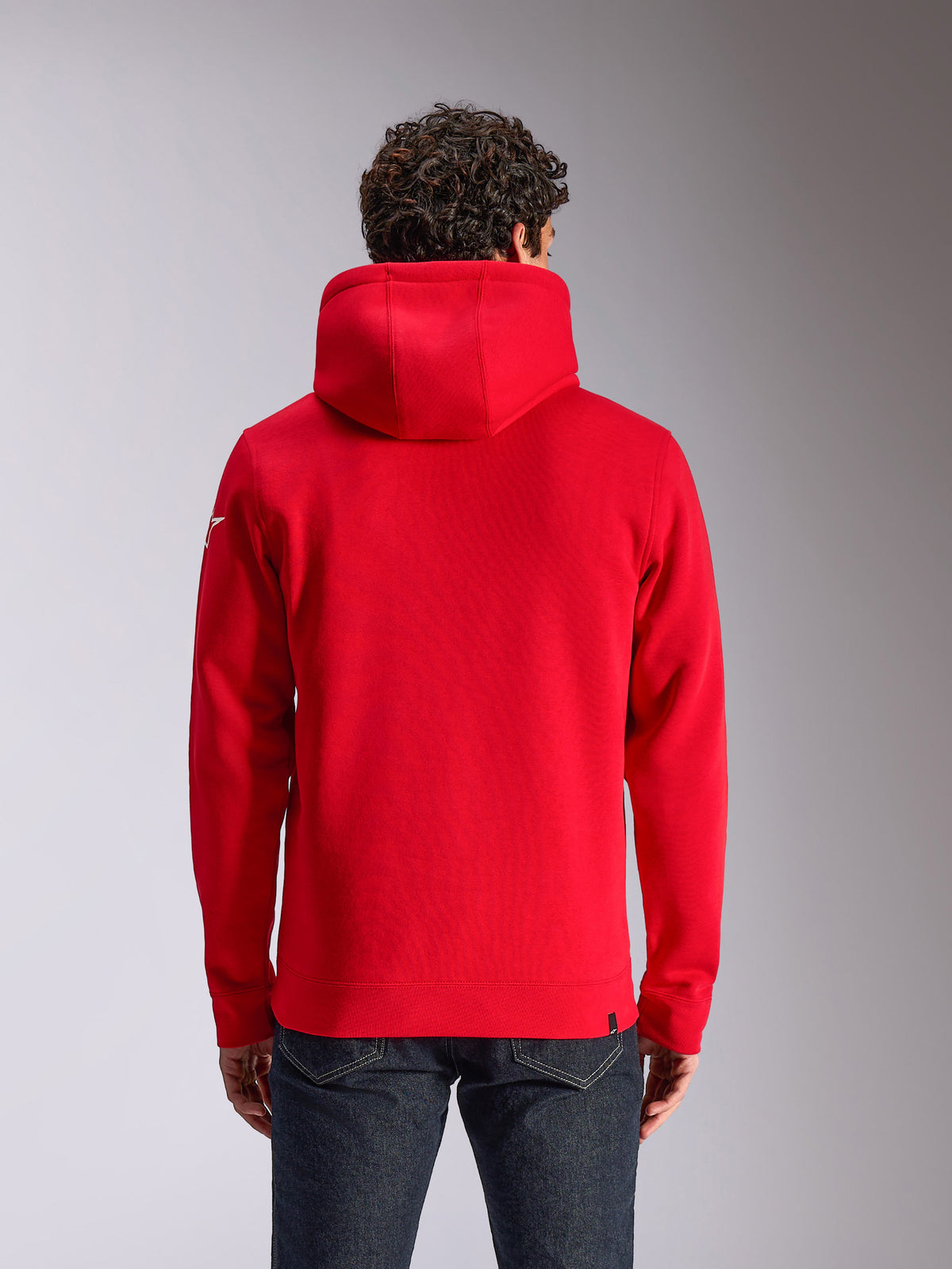 Alpinestars Linear Wordmark V3 Hoodie, vista posteriore di una felpa rossa con cappuccio, con logo Ageless bianco sulla manica, polsini e orlo a coste, streetwear casual ispirato al motorsport