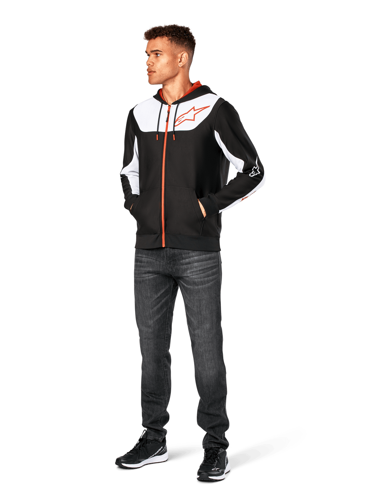 Felpa con cappuccio Alpinestars Sessions V3, felpa casual con zip frontale, nero, bianco e rosso, indossata da un modello con jeans scuri e sneakers nere, caratterizzata da pannelli color-block bianchi sul petto e sulle maniche, dettagli della zip e dei cordini rossi, grande logo sul petto, streetwear in pile di poliestere ispirato al motorsport.