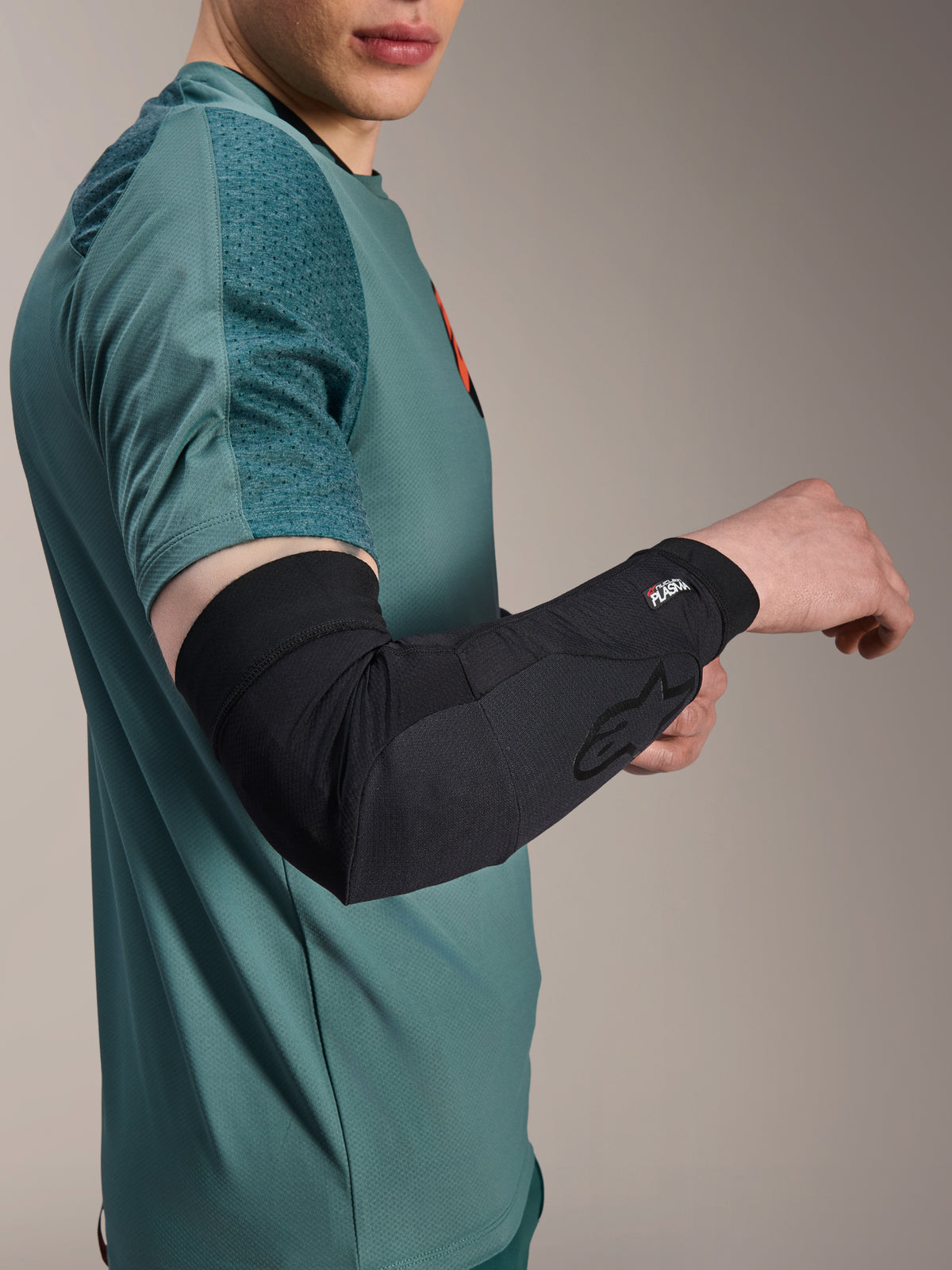 Alpinestars A-Motion Plasma Elbow Sleeve, protezione gomito da ciclismo, nero, indossata da un rider con maglia verde acqua, con logo Alpinestars e marchio Nucleon Plasma, design sottile e traspirante per protezione MTB