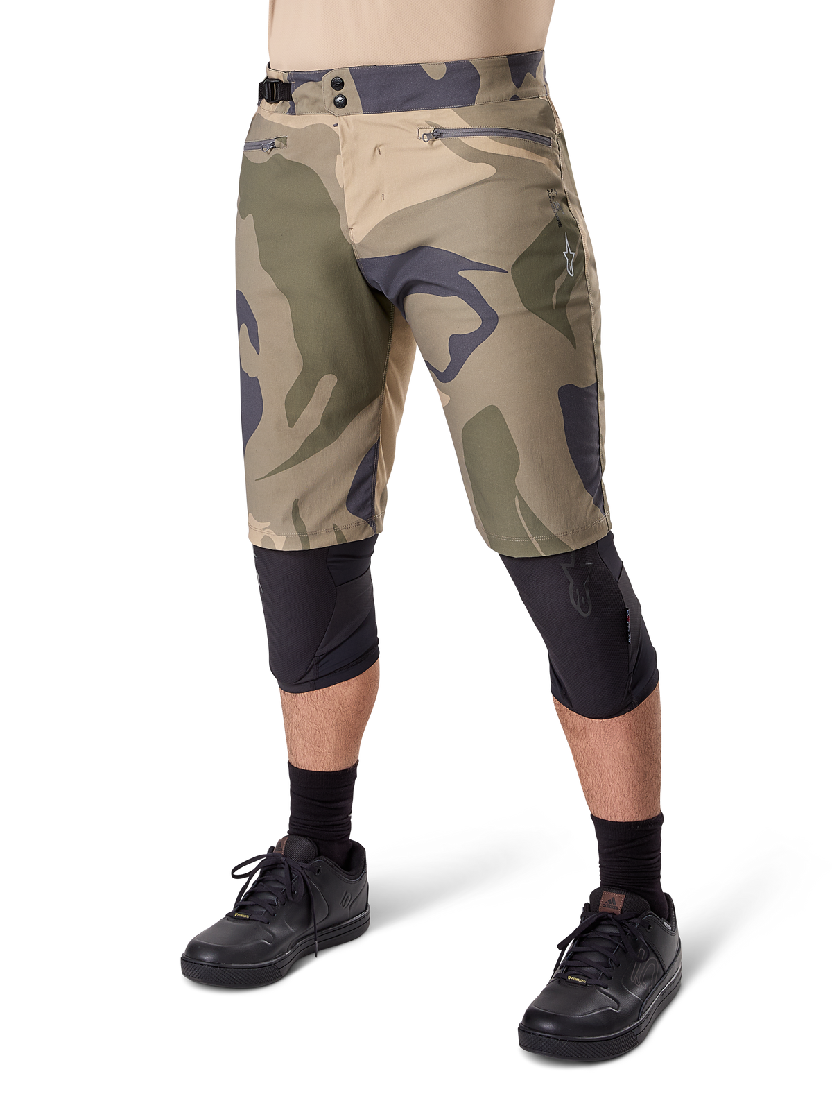 Alpinestars A-Dura Camo Liner Short, pantaloncini da mountain bike, fantasia mimetica marrone, vista frontale con tasche con zip e regolatori laterali in vita, indossati con ginocchiere nere e scarpe da ciclismo nere, attrezzatura resistente per MTB