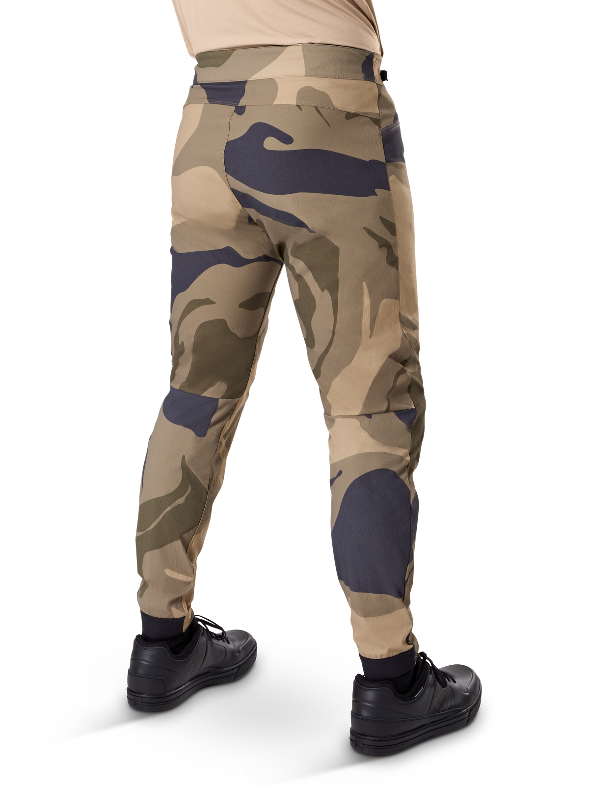 Alpinestars A-Dura Camo Pant, pantaloni MTB, motivo mimetico marrone con accenti sabbia e grigio scuro, vista posteriore con sneaker nere, gambe affusolate e polsini elasticizzati, tessuto resistente elasticizzato in 2 direzioni per mountain bike