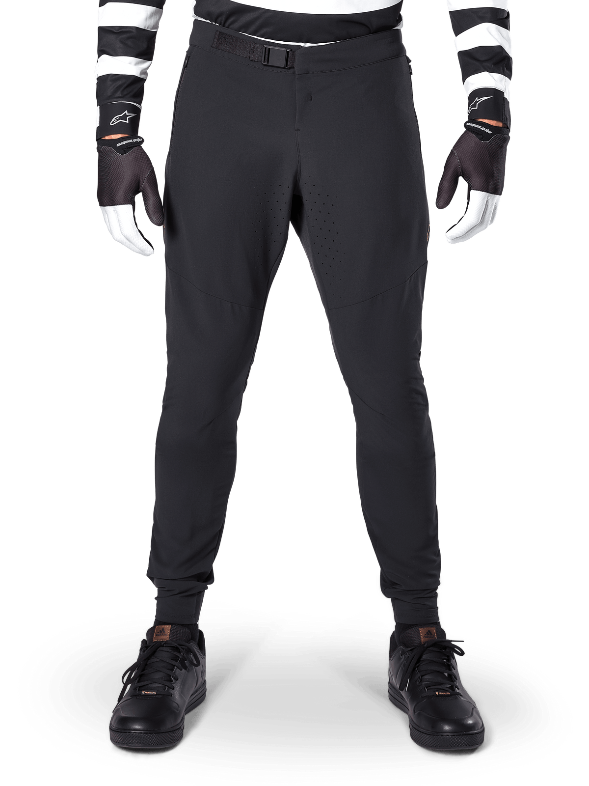 Alpinestars A-Aria Elite Pants, pantaloni da mountain bike, nero, vista frontale con perforazioni laser e chiusura con fibbia magnetica, indossati con maglia a righe bianche e nere e guanti neri, abbigliamento tecnico da ciclismo per trail riding