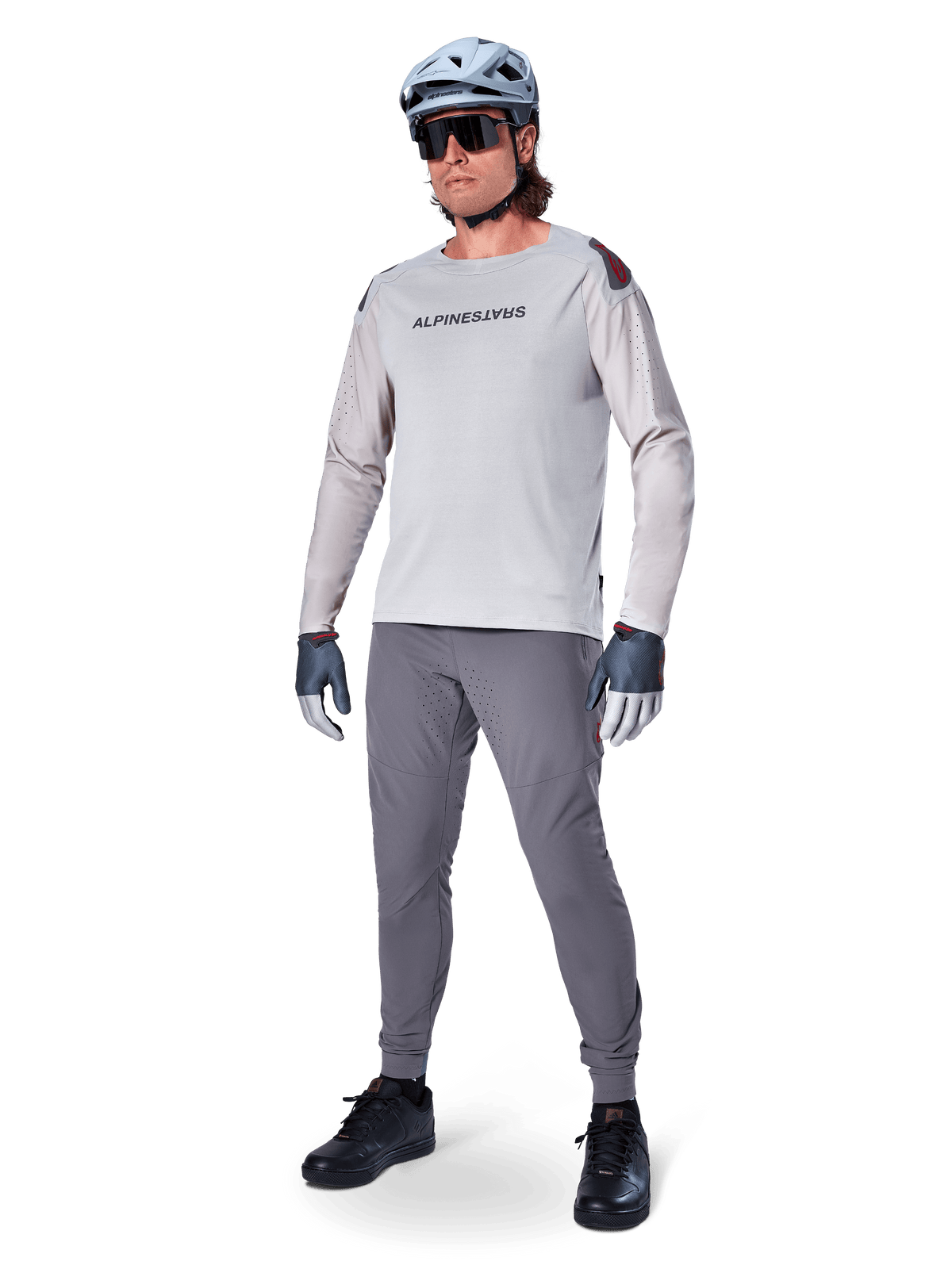 Pantaloni Alpinestars A-Aria Elite, pantaloni MTB grigio scuro, indossati da un rider con maglia a maniche lunghe grigio chiaro e casco grigio, con fori di ventilazione laser sulle cosce e vestibilità tecnica affusolata per mountain bike