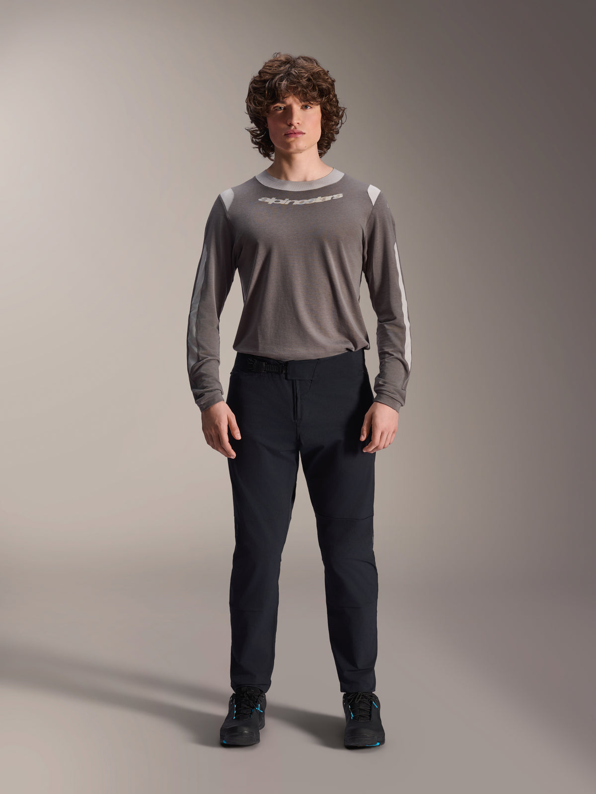 Alpinestars A-Dura Elite Pants, pantaloni da mountain bike neri, abbigliamento tecnico da ciclismo con vestibilità regolare, indossati con una maglia grigia a maniche lunghe e scarpe nere, resistente struttura in Cordura® per la guida fuoristrada