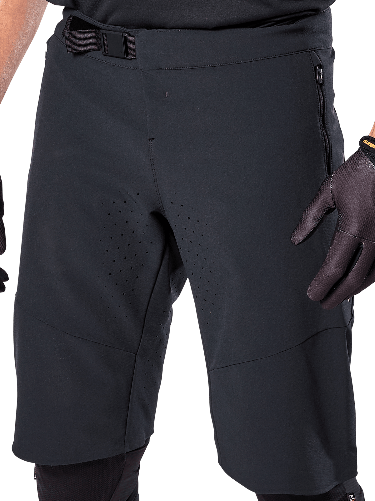 Pantaloncini Alpinestars A-Aria Elite in nero, vista ravvicinata della zona vita e coscia, con chiusura a fibbia magnetica, tasche con zip e perforazioni di ventilazione tagliate al laser, indossati con guanti da ciclismo neri per mountain bike.