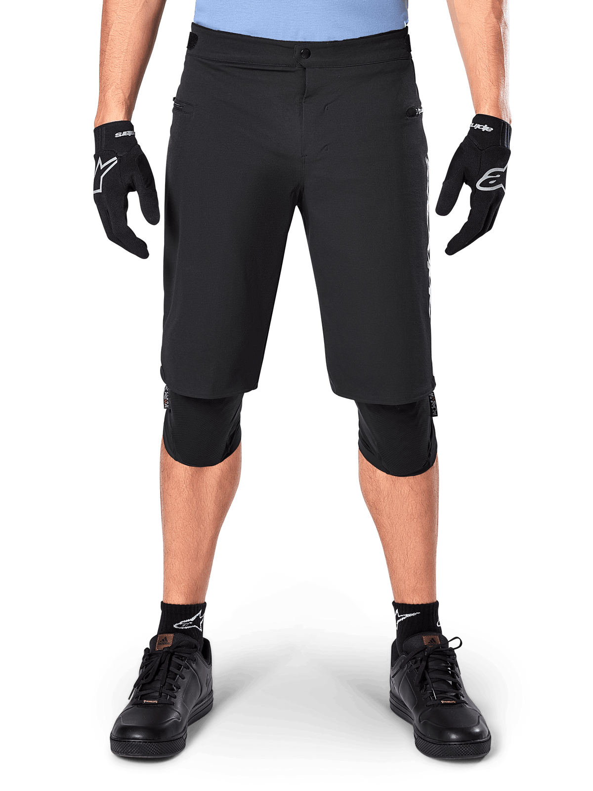 Pantaloncini Alpinestars A-Dura Elite, pantaloncini da mountain bike neri, indossati da un ciclista con guanti e ginocchiere neri, dotati di chiusura frontale a scatto e tasche con zip, in resistente materiale Cordura per il ciclismo fuoristrada