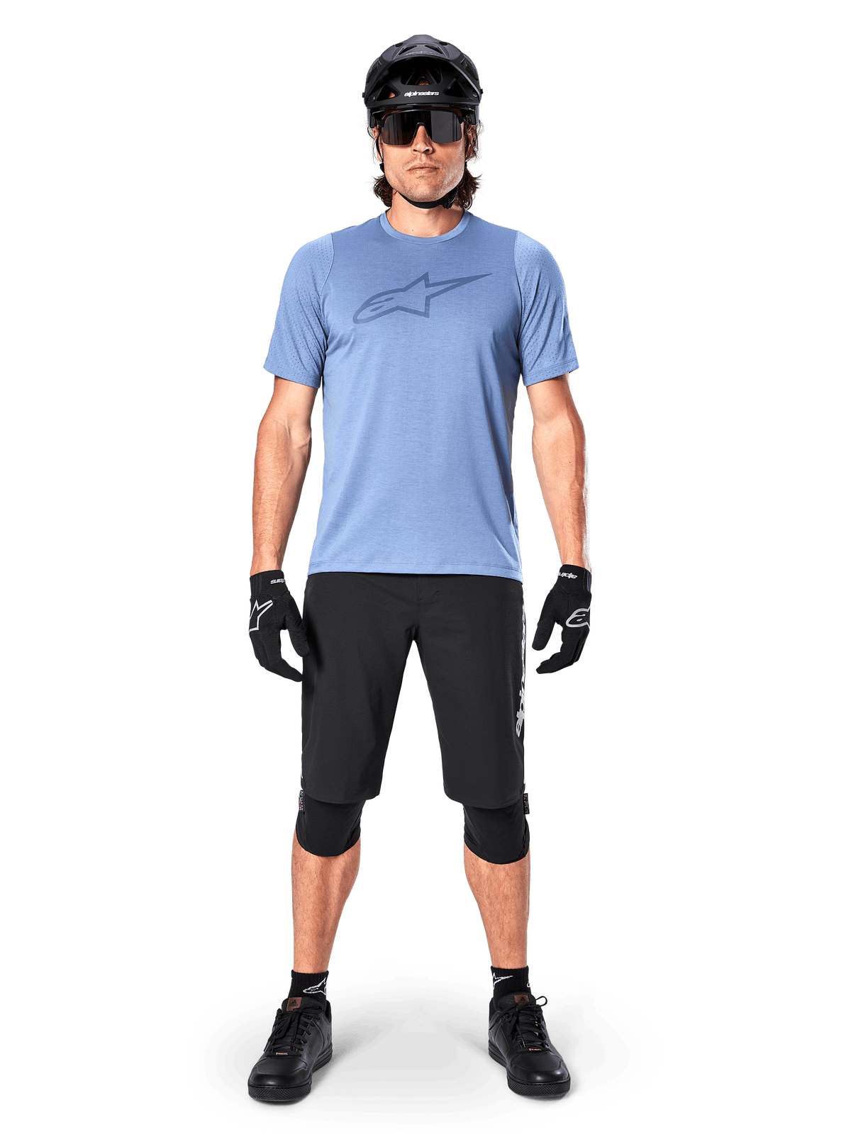 Alpinestars Pantaloncini A-Dura Elite, pantaloncini da mountain bike neri, indossati con una t-shirt azzurra, casco nero, occhiali da sole e ginocchiere, abbigliamento professionale per ciclismo fuoristrada