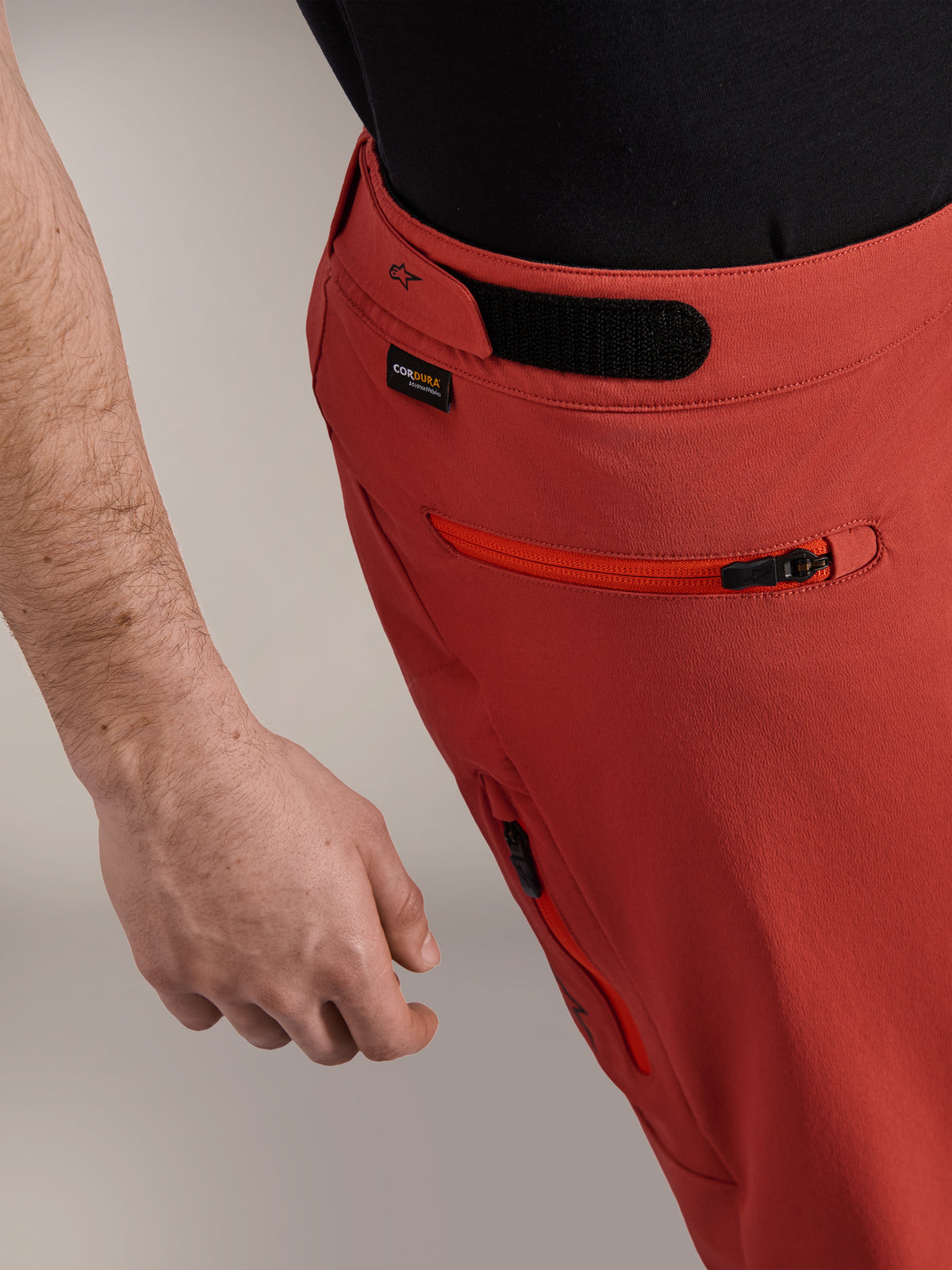 Pantaloncini Alpinestars A-Dura Elite, arancione scuro, primo piano del profilo laterale con regolatore in vita a gancio e asola, logo Cordura® e tasca laterale con zip, pantaloncini da mountain bike premium