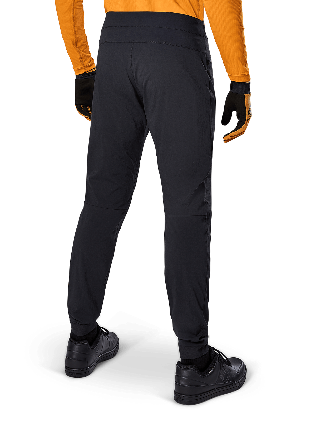 Alpinestars A-Dura Pants, pantaloni MTB neri, vista posteriore, indossati con una maglia a maniche lunghe arancione e guanti neri, con polsini elasticizzati e materiale tessile resistente per la mountain bike.