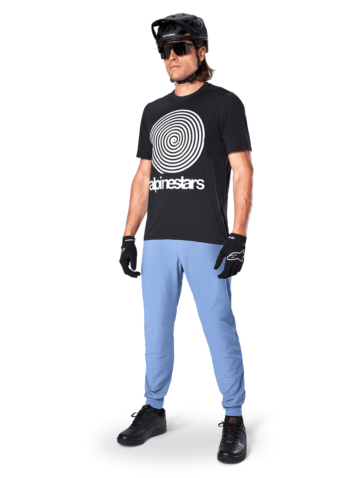Pantaloni Alpinestars A-Dura, pantaloni da MTB, Infinity Blue, indossati con t-shirt grafica nera con logo a spirale bianco, casco nero, occhiali da sole e guanti neri, abbigliamento professionale da mountain bike