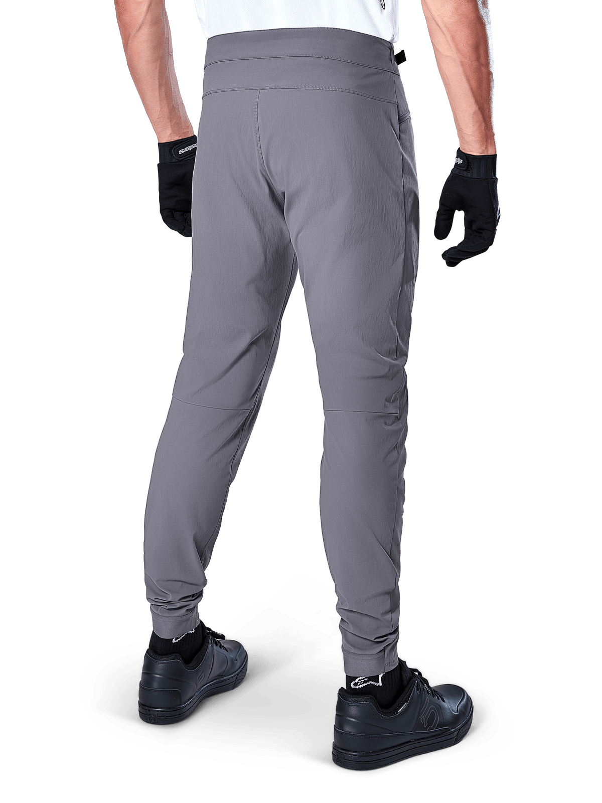 Alpinestars A-Dura Pants, pantaloni da mountain bike, grigio scuro, vista posteriore del modello che indossa l'attrezzatura, con un resistente tessuto elasticizzato in 2 direzioni e polsini elasticizzati, abbinati a guanti e sneaker neri per un look pronto per il ciclismo