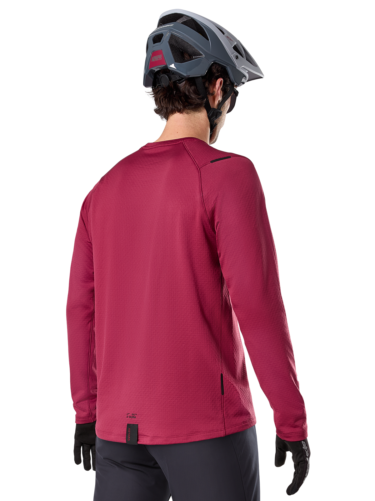 Alpinestars A-Dura Thermal Jersey, maglia da mountain bike a maniche lunghe, bordeaux, vista posteriore su modello con casco da MTB grigio e guanti neri, con coda allungata e piccoli dettagli del logo, progettata per il trail riding in climi freddi
