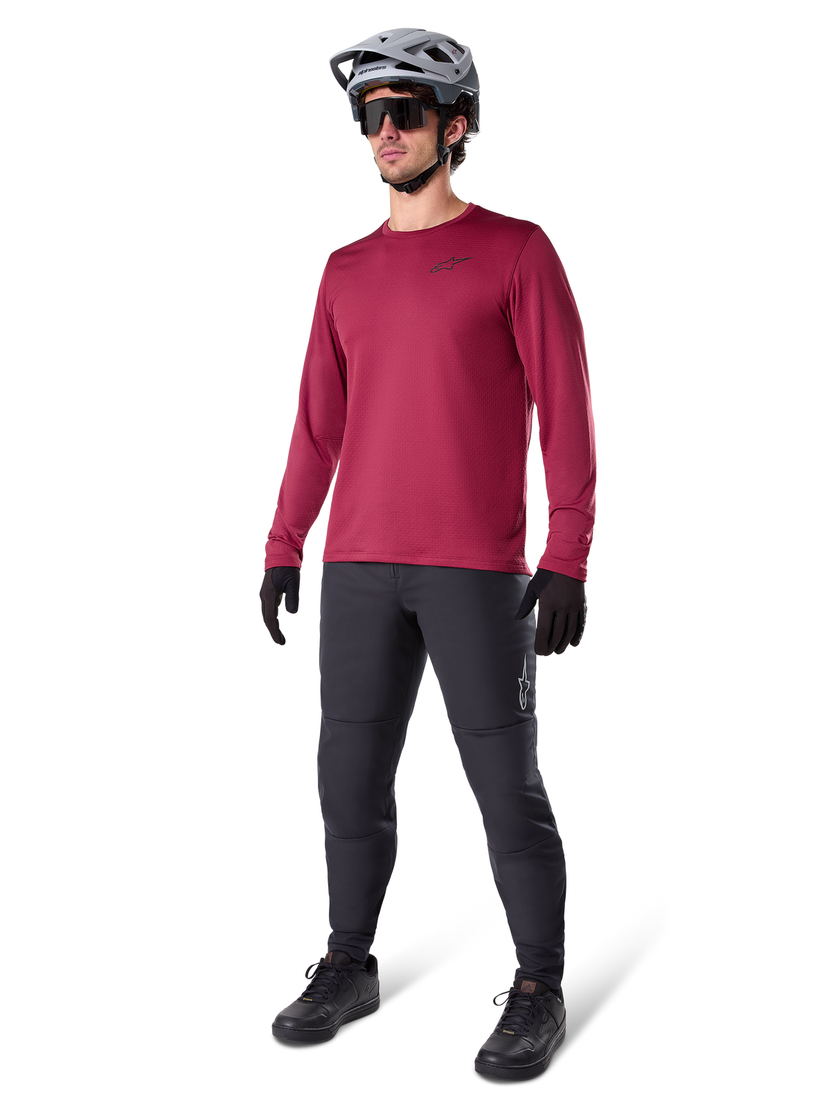 Maglia termica Alpinestars A-Dura in bordeaux, maglia da ciclismo a maniche lunghe isolante, indossata con pantaloni da mountain bike grigio scuro, guanti neri e casco grigio, scatto in studio a figura intera di abbigliamento MTB per il freddo