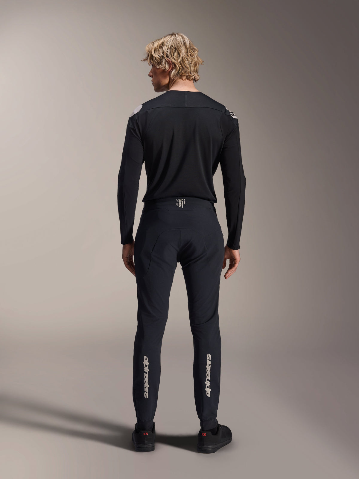 Alpinestars Maglia A-Aria Polartec Elite a maniche lunghe, maglia da MTB nera, vista posteriore indossata con pantaloni neri coordinati, vestibilità performante per mountain bike, con tessuto tecnico traspirante e branding discreto sulla parte bassa della schiena