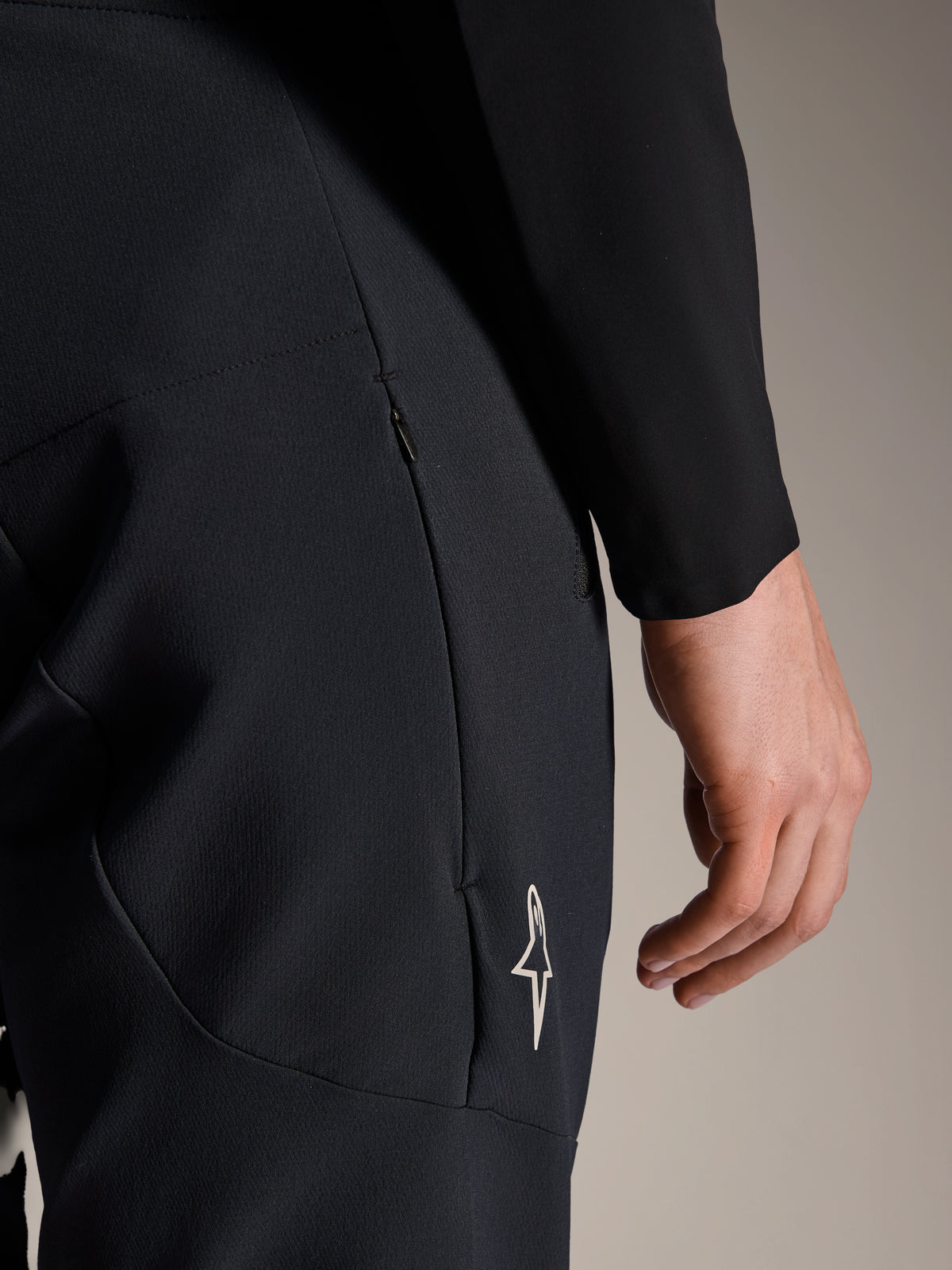 Dettaglio dei pantaloni Alpinestars A-Aria Elite in Black Titanium, con tasca laterale con zip e piccolo logo a stella bianco, pantaloni tecnici da mountain bike progettati per il ciclismo ad alte prestazioni