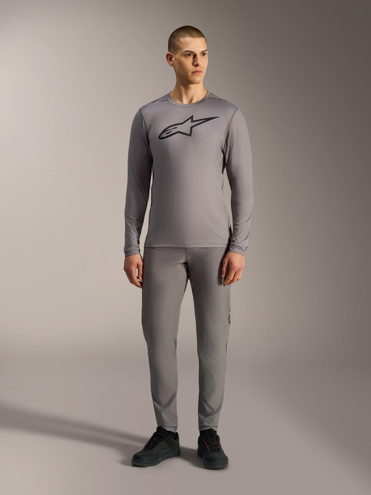 Alpinestars A-Dura Ride Maglia maniche lunghe grigia con logo nero sul petto, abbinata a pantaloni MTB coordinati.