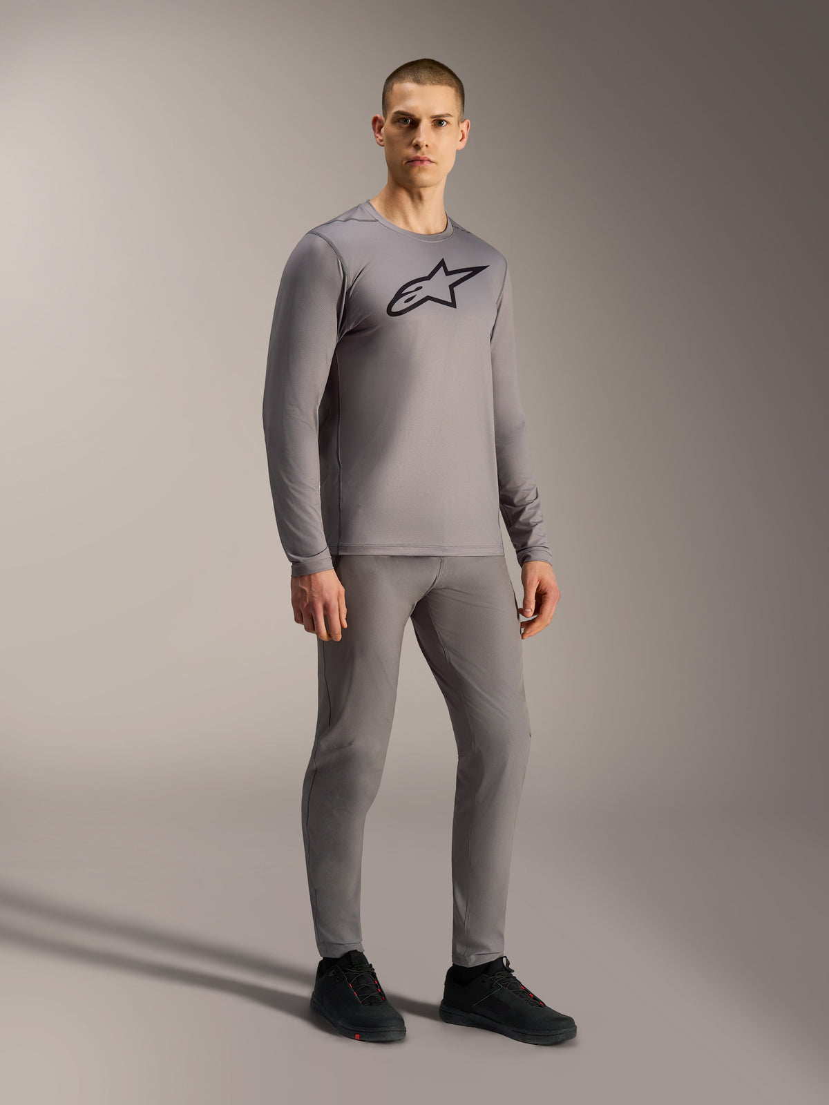 Maglia grigia A-Dura Ride a maniche lunghe con logo nero, indossata per un look completo da mountain bike.