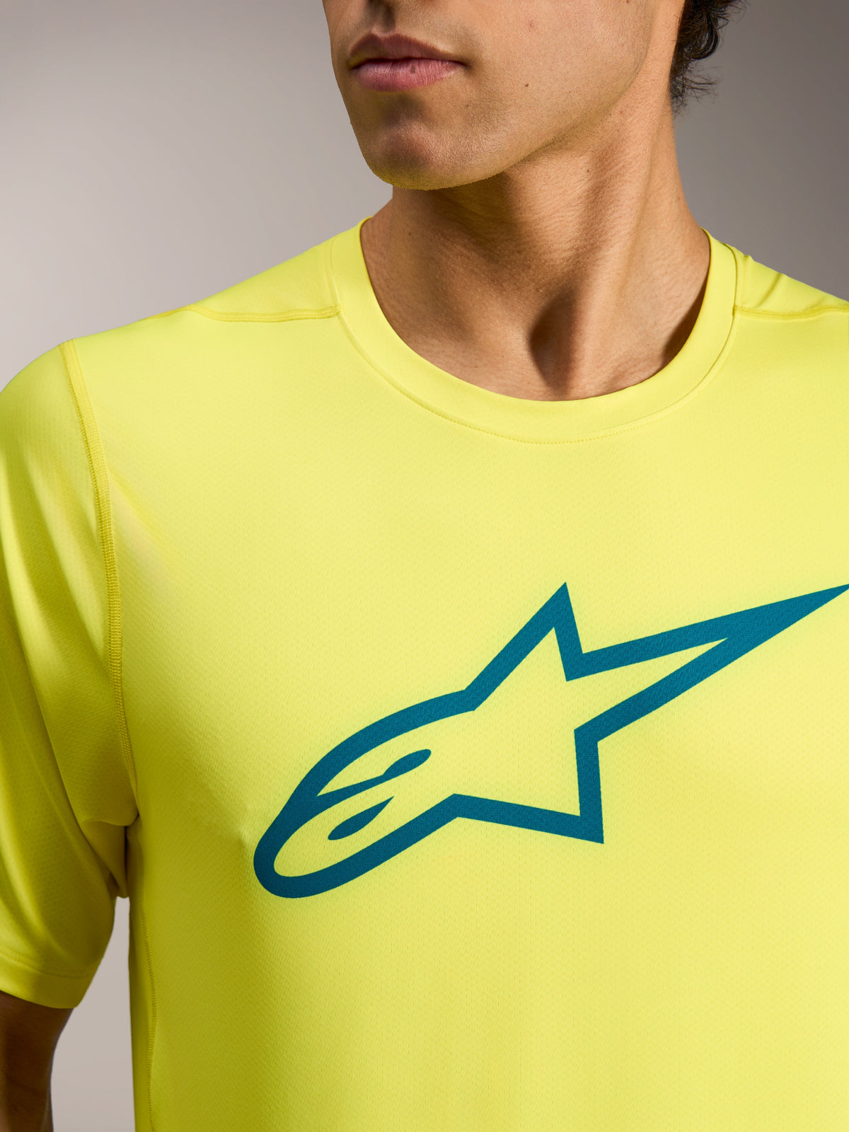 Maglia Alpinestars A-Dura Ride giallo fluo con logo Astars teal sul petto, abbigliamento tecnico leggero da MTB.