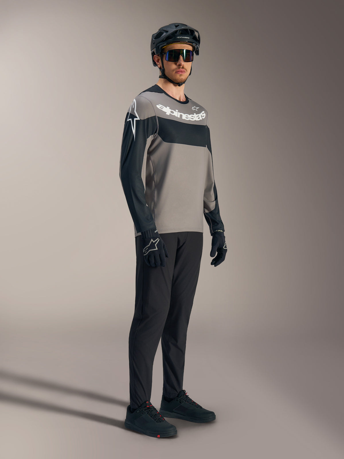 Maglia a maniche lunghe A-Dura Race grigia e nera con loghi bianchi, pantaloni tecnici da MTB e casco.