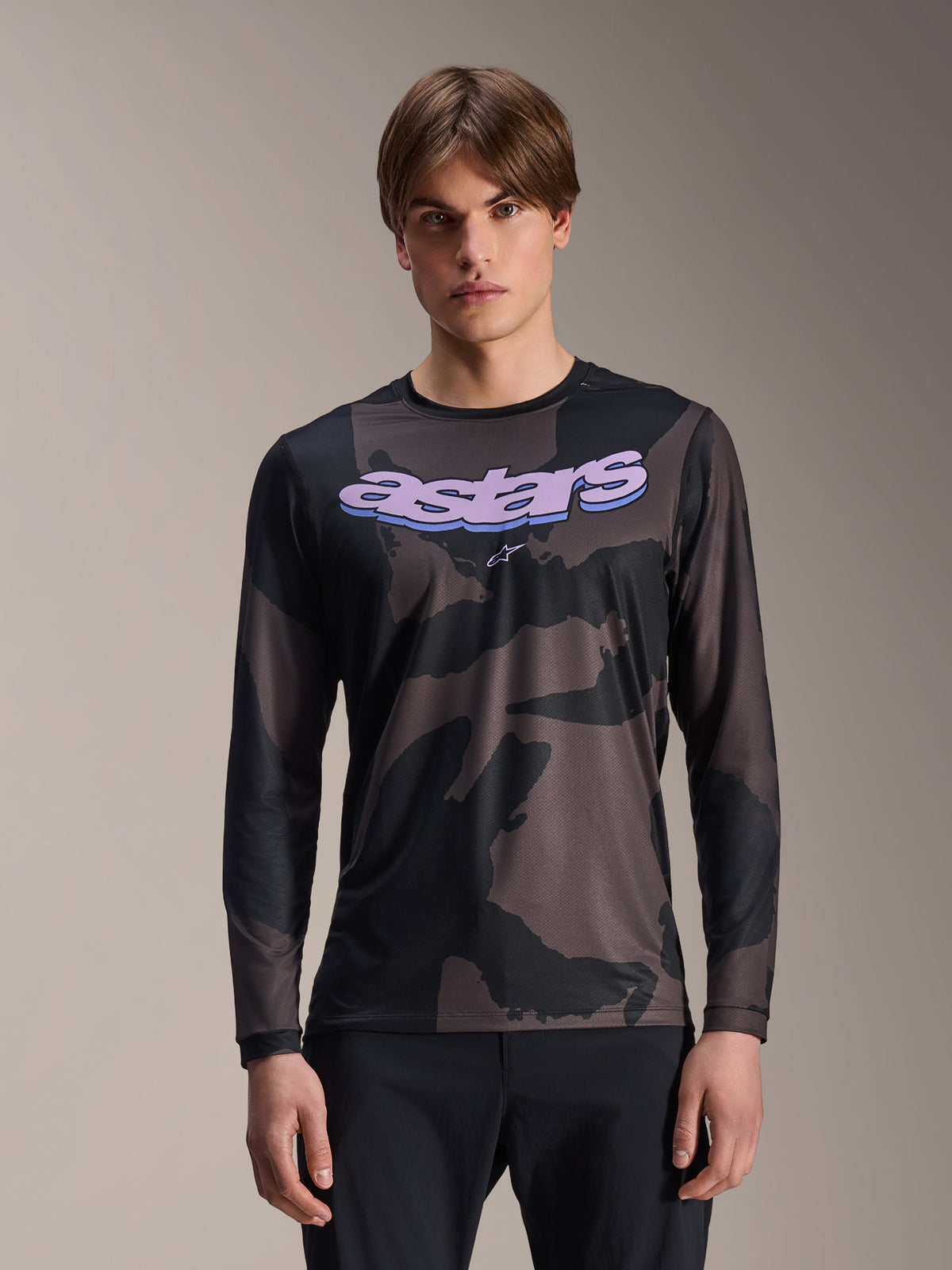 Alpinestars A-Dura Hollow Camo Long Sleeve Jersey, maglia da mountain bike MTB, motivo mimetico nero e grigio, grafica 'astars' viola sul petto, indossata da un modello con pantaloni neri, design casual e performante