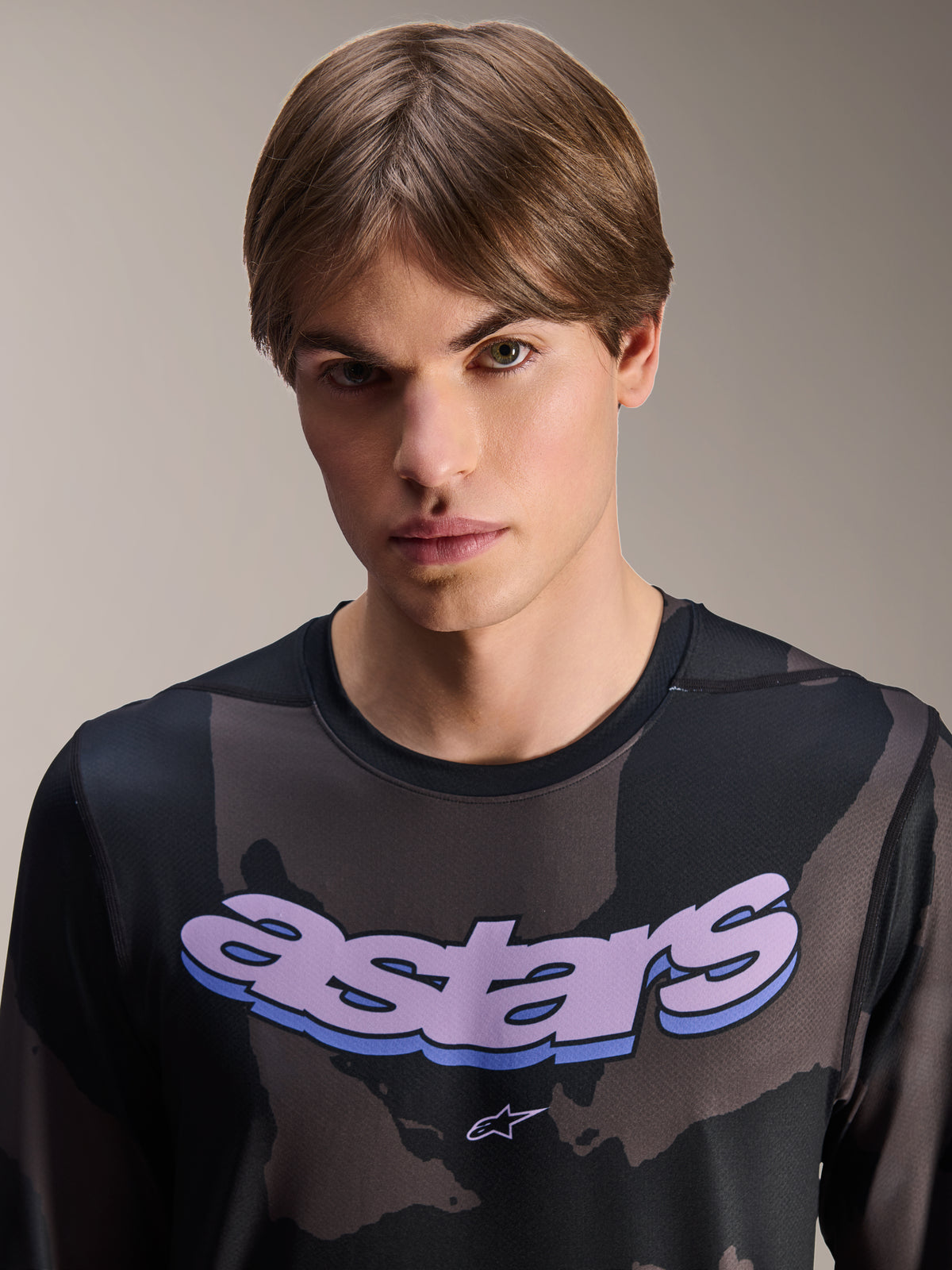 Maglia Alpinestars A-Dura Hollow Camo - Maniche Lunghe, Black Camo con grafica 'astars' viola sul petto, scatto in studio di un modello che indossa abbigliamento MTB, stile casual e tecnico da mountain bike