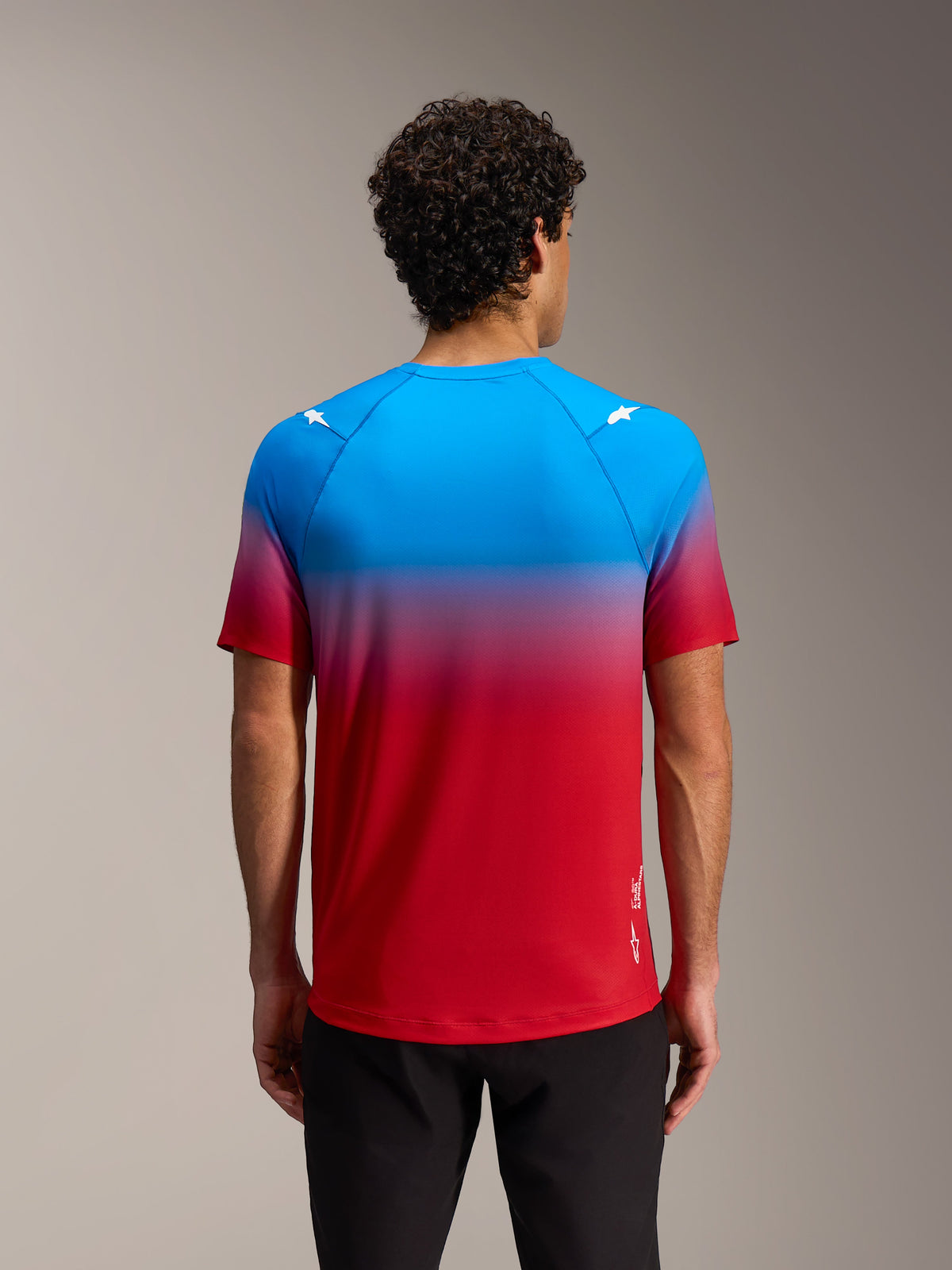 Maglia MTB Alpinestars A-Dura ASTARS 2.0 con sfumatura rosso-blu, loghi a stella sulle spalle, vista posteriore.