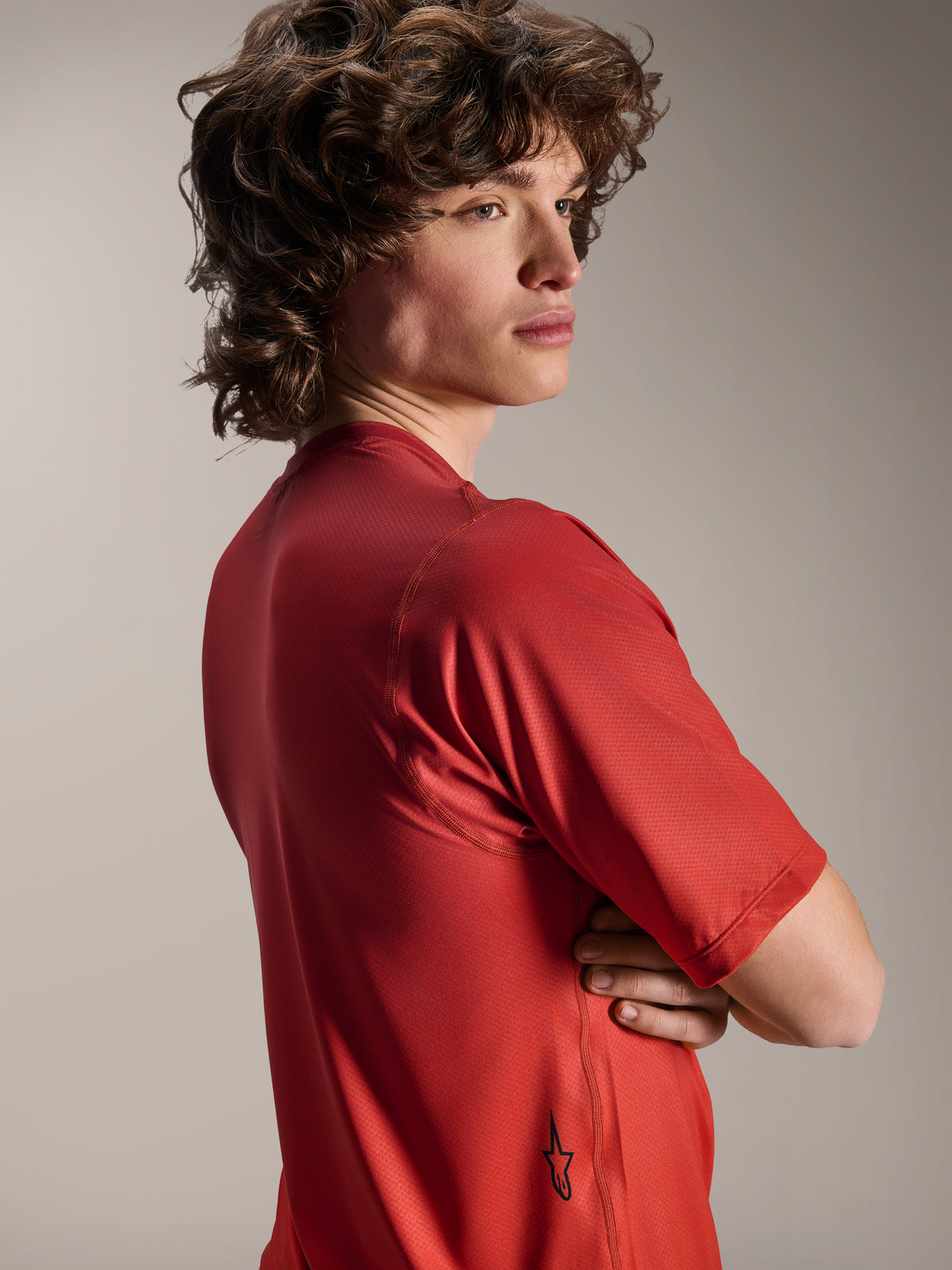Alpinestars Maglia A-Dura Rise a maniche corte, Spicy Orange, vista laterale e posteriore del modello, con un piccolo logo Astars nero sull'orlo inferiore, tessuto jacquard leggero e strutturato per prestazioni MTB