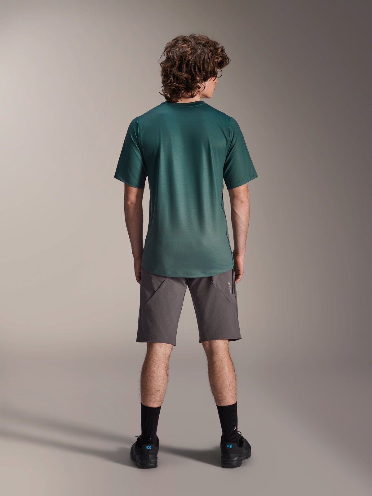 Maglia Alpinestars A-Dura Rise - a maniche corte, Verde Silver Pine, vista posteriore di un modello che indossa la maglia con pantaloncini grigi e calze nere, con coda più lunga e vestibilità regolare per mountain bike