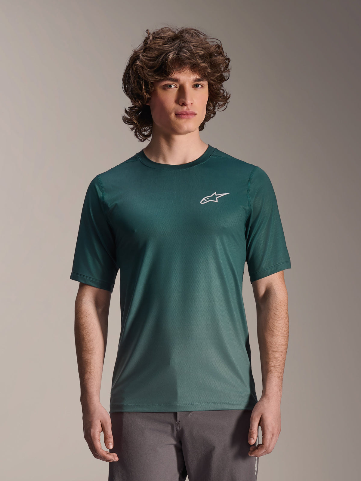 Alpinestars A-Dura Rise Jersey a maniche corte, verde scuro Silver Pine, indossata da un modello, con logo Astars bianco sul petto, tessuto jacquard leggero traspirante, maglia tecnica casual per mountain bike