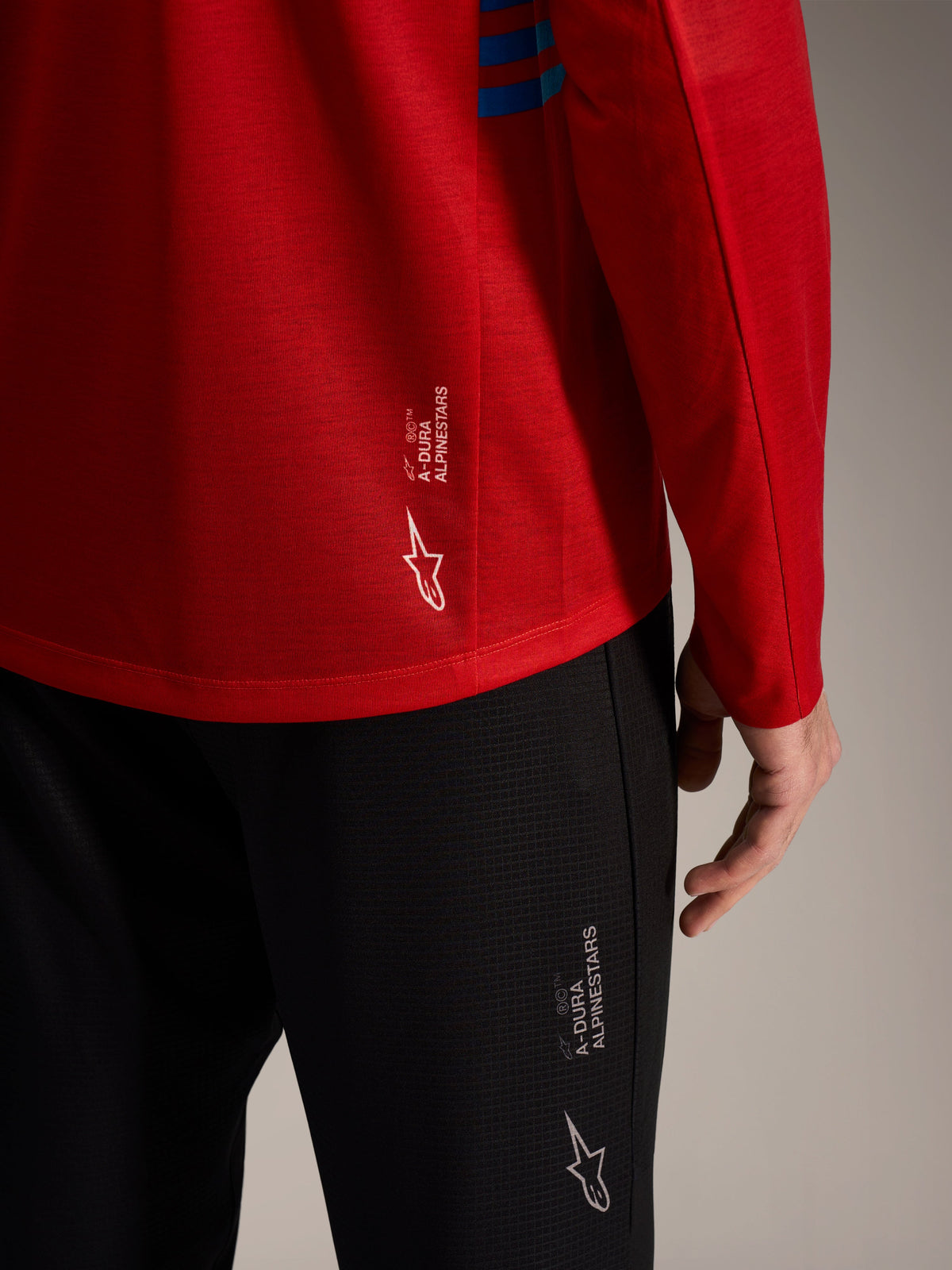 Maglia rossa a maniche lunghe A-Dura Elite 2.0 e pantaloni MTB neri con loghi Alpinestars e tessuto tecnico.