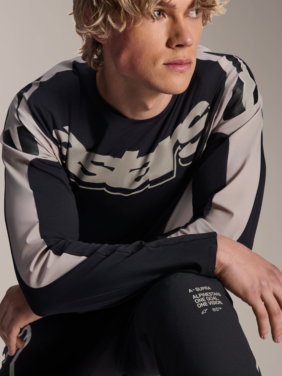 Alpinestars A-Supra Melt Jersey, maglia da MTB a maniche lunghe, nera con grafiche grigio chiaro, indossata da un modello, con logo vistoso sul petto e scritta "One Goal. One Vision.", abbigliamento tecnico per mountain bike