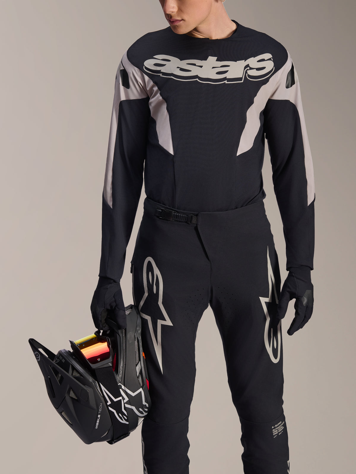 Kit da gara MTB Alpinestars A-Supra Melt, maglia a maniche lunghe e pantaloni, nero e grigio con loghi Astars bianchi, modello con casco integrale nero e guanti coordinati, abbigliamento ad alte prestazioni per mountain bike downhill ed enduro