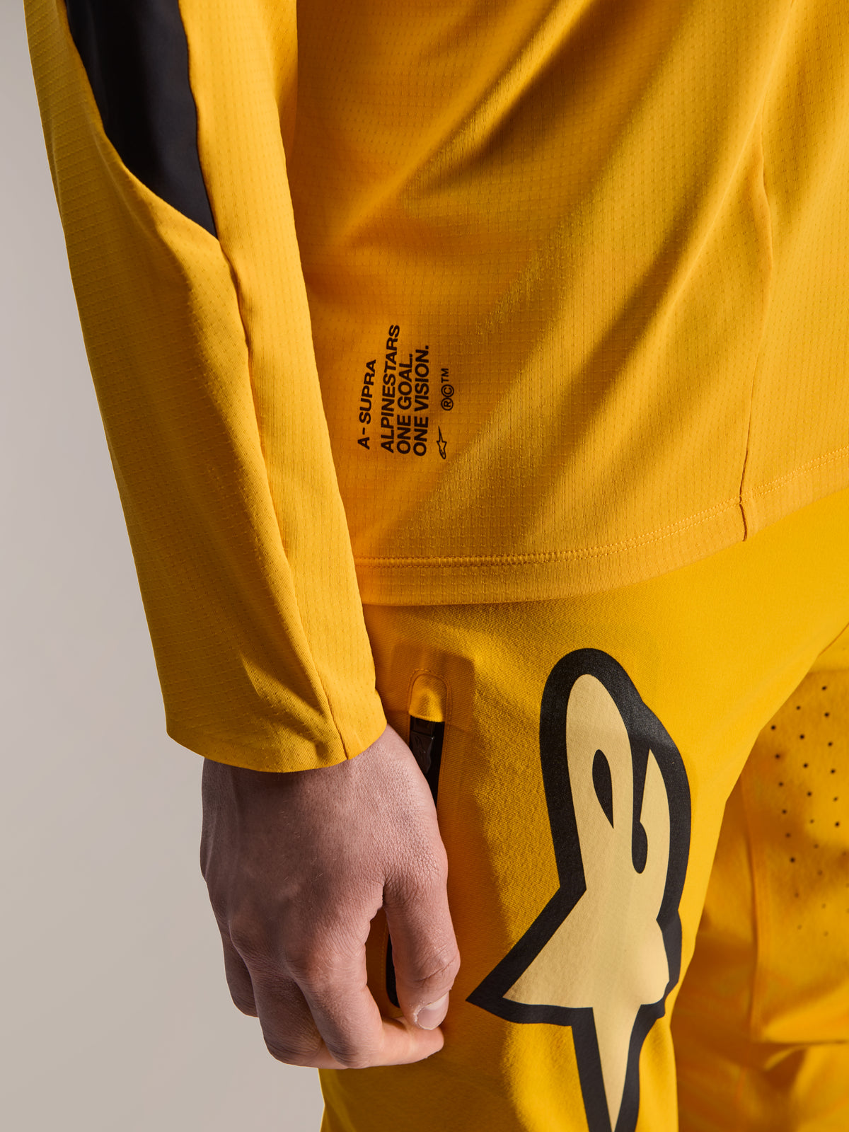 Alpinestars Limited Edition A-Supra Melt Gold Pants e maglia LS coordinata, giallo scuro, vista ravvicinata con marchio 'One Goal. One Vision.' e grande logo stilizzato sulla coscia, equipaggiamento MTB ad alte prestazioni