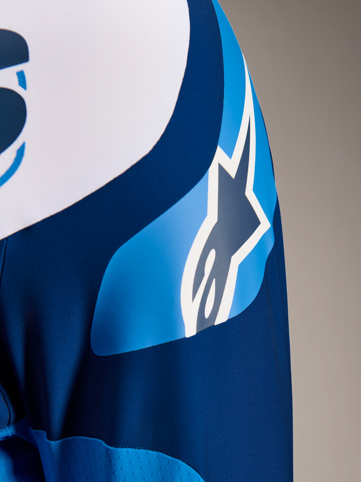Alpinestars A-Supra Melt Jersey, maglia MTB a maniche lunghe blu, primo piano della manica con grafica del logo ASTARS e tessuto microforato per la ventilazione