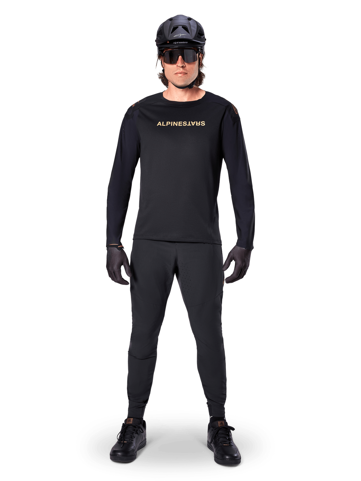 Alpinestars A-Aria Polartec Switch Long Sleeve Jersey, maglia a maniche lunghe, nero, indossata da un rider con pantaloni tecnici neri coordinati, casco nero, occhiali da sole e guanti neri, attrezzatura MTB per percorsi fuoristrada