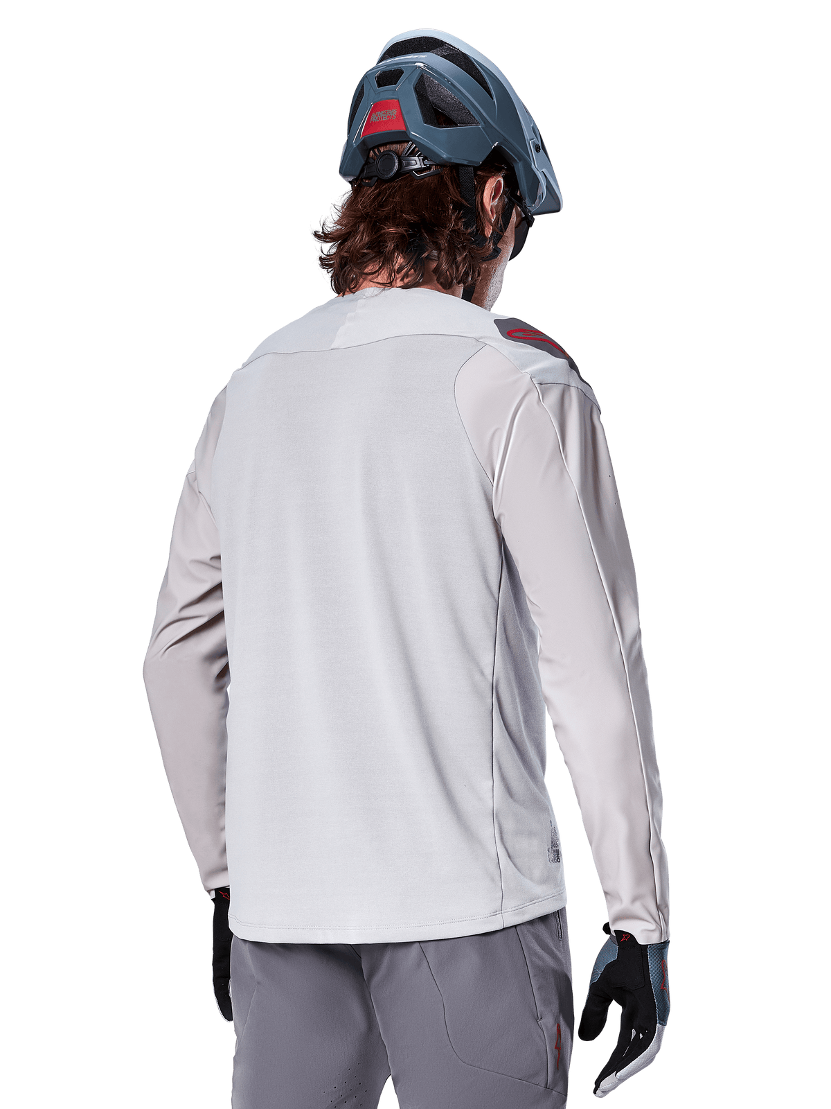 Alpinestars A-Aria Polartec Switch Long Sleeve Jersey, Grigio Chiaro, vista dal retro su un pilota, indossata con casco blu da mountain bike e pantaloni grigi, abbigliamento tecnico da mountain bike per percorsi off-road