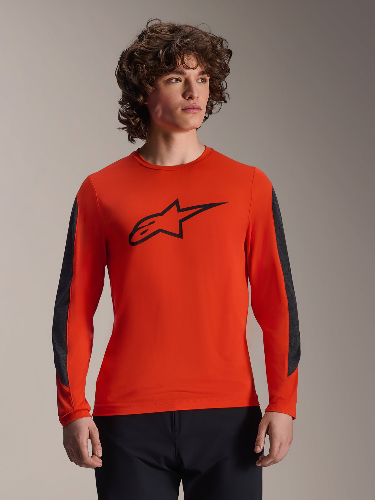 Alpinestars A-Dura Insert Astar Jersey - Long Sleeve, maglia da MTB a maniche lunghe, arancione con logo stella nero e inserti grigio scuro sulle maniche, indossata da un modello, abbigliamento tecnico da ciclismo