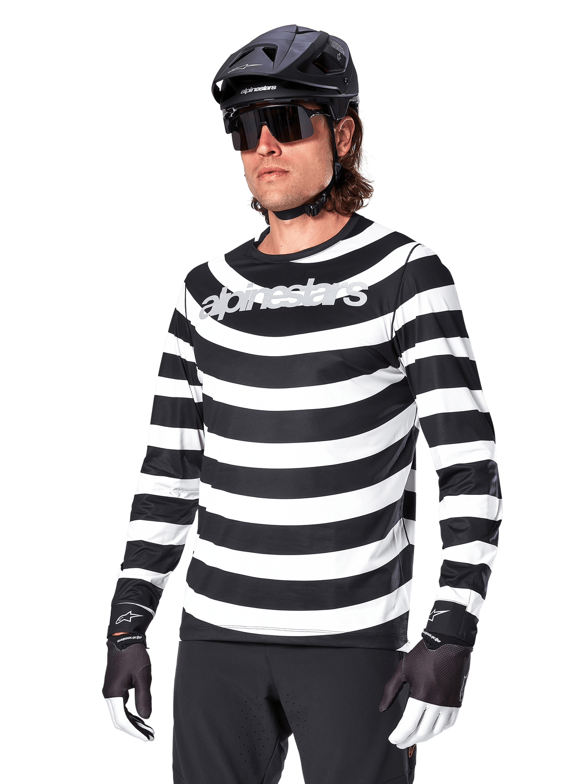 Alpinestars A-Aria Oscar Jersey a maniche lunghe, maglia da ciclismo MTB, a righe orizzontali bianche e nere, indossata con casco nero e occhiali da sole, con logo Alpinestars sul petto, abbigliamento tecnico per mountain bike
